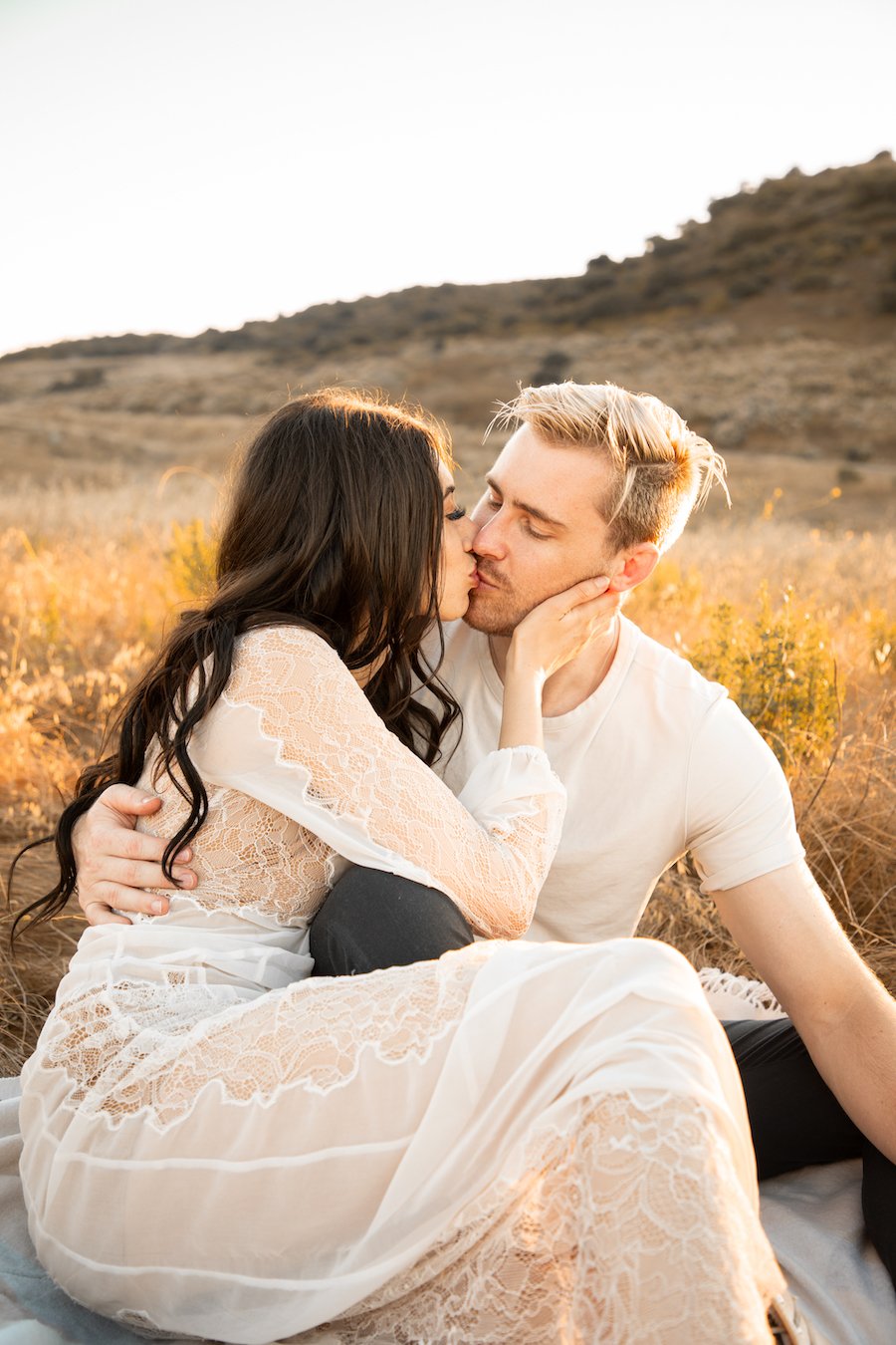 Man and woman kissing in a golden field for California engagement photos