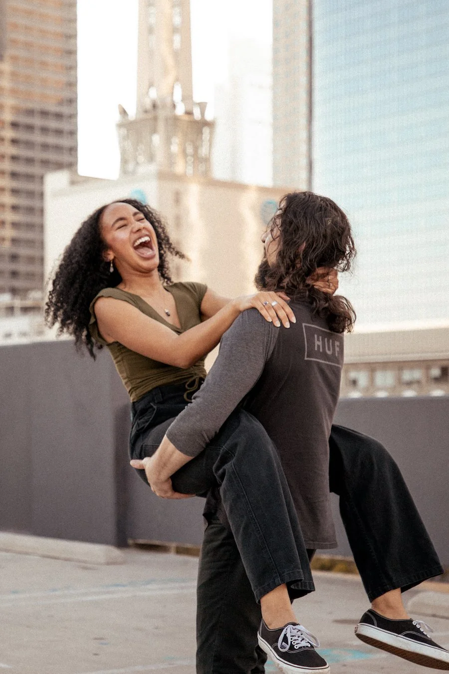 man holding woman spinning on rooftop in downtown los angeles photoshoot