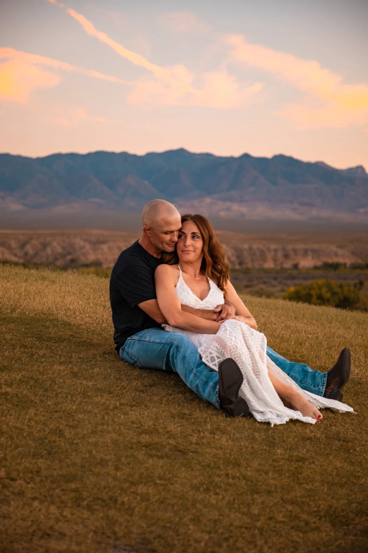 couple sitting on grass embracing for desert engagement photos