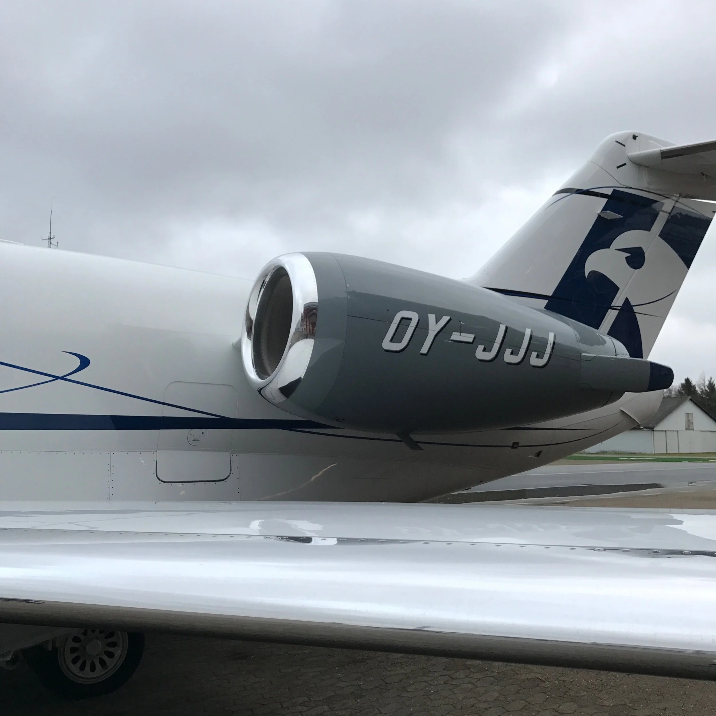 Close-up of an airplane's engine and part of the fuselage, with a cloudy sky overhead.