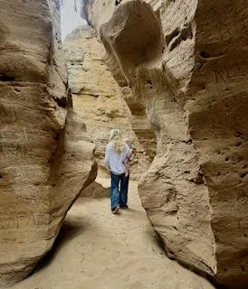 Person walking through a narrow canyon with tall rock walls on either side.