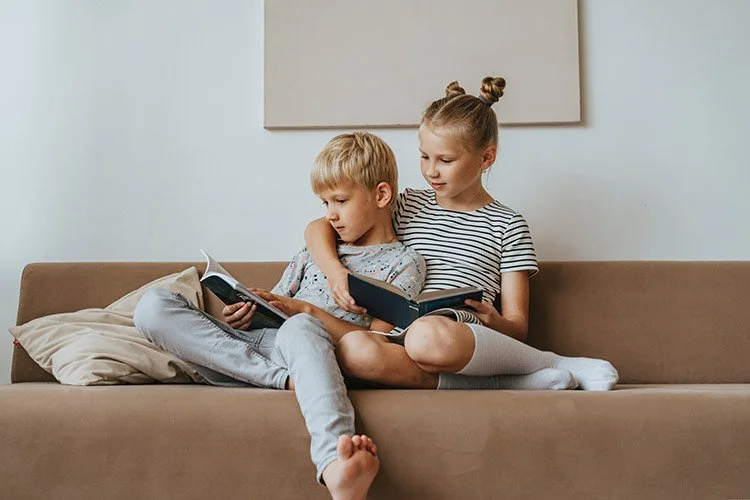 Kids cuddled on the sofa reading books