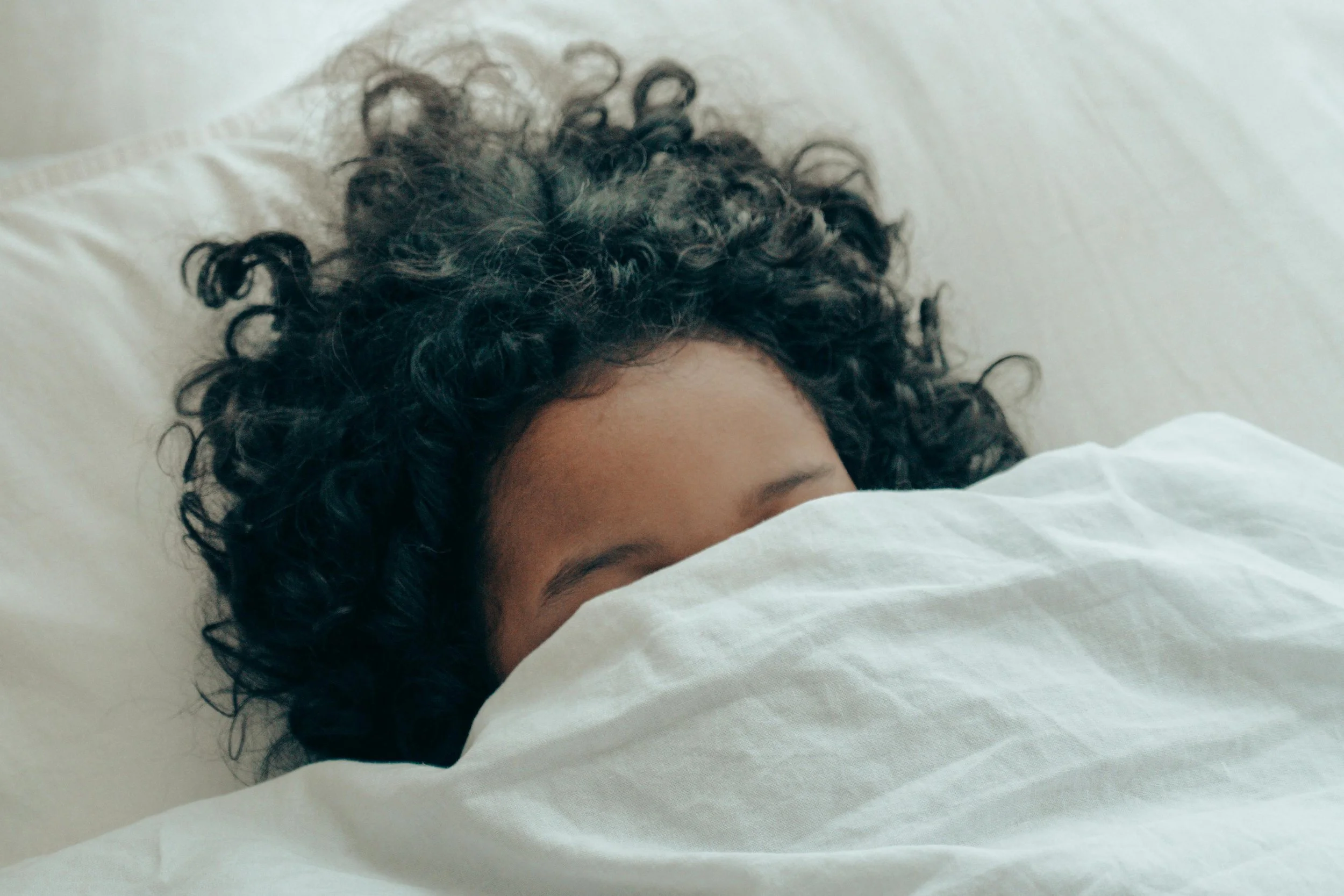 Person in bed with blanket covering face