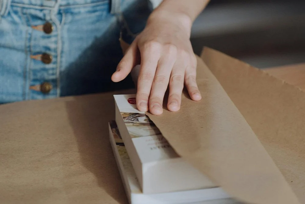 Person wrapping a book in brown paper