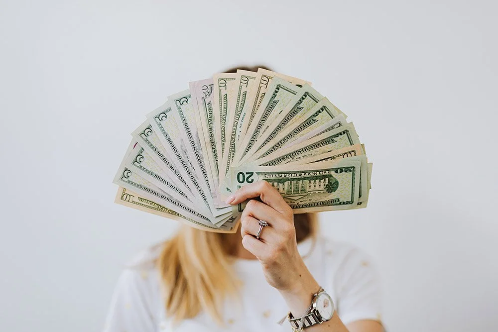Person holding paper money up in front of face