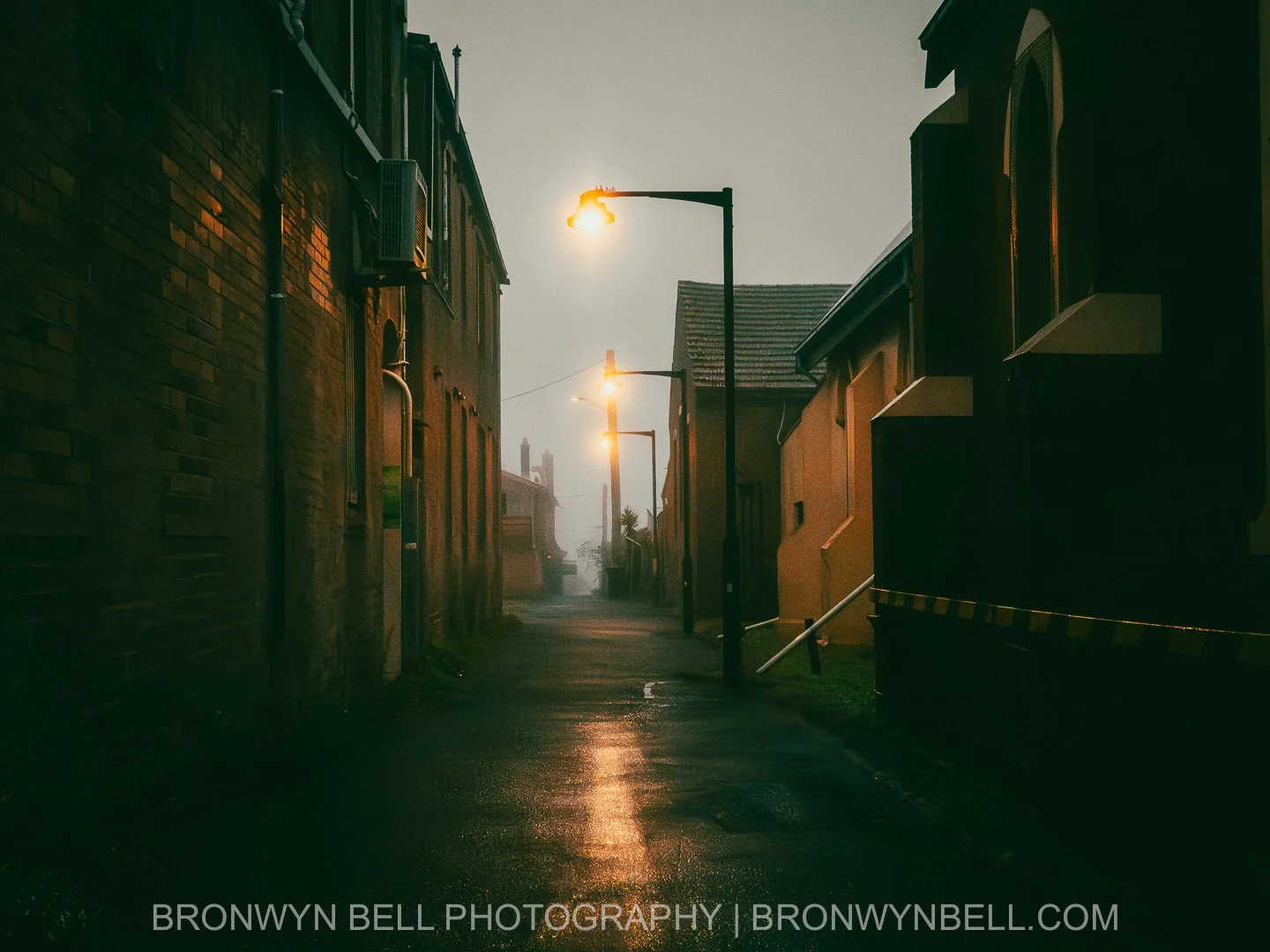 Empty side street in Katoomba during a foggy winter morning, muted light and wet asphalt creating a quiet, atmospheric scene.