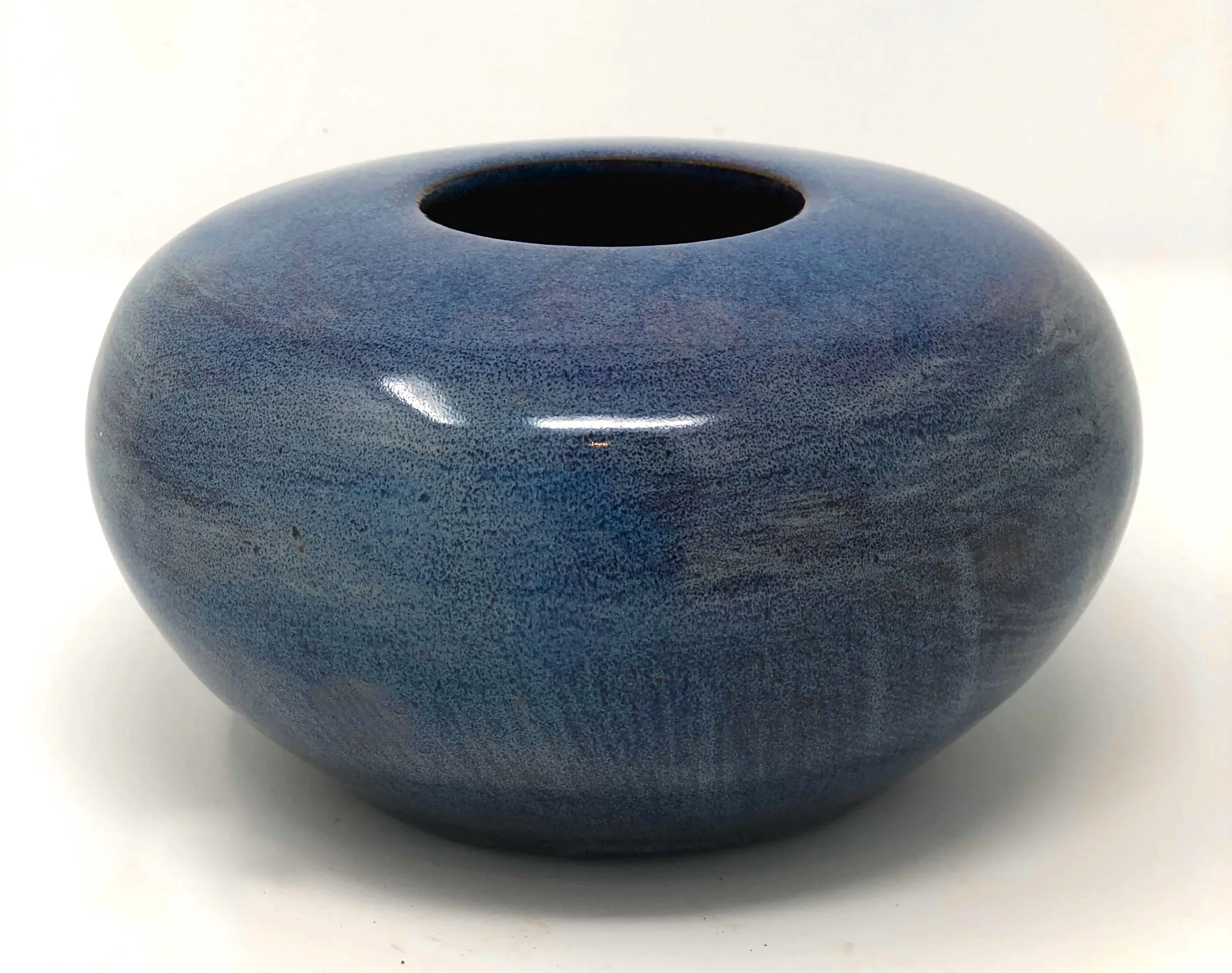 A smooth, rounded, dark gray ceramic vase with a small circular opening at the top, set against a plain white background.