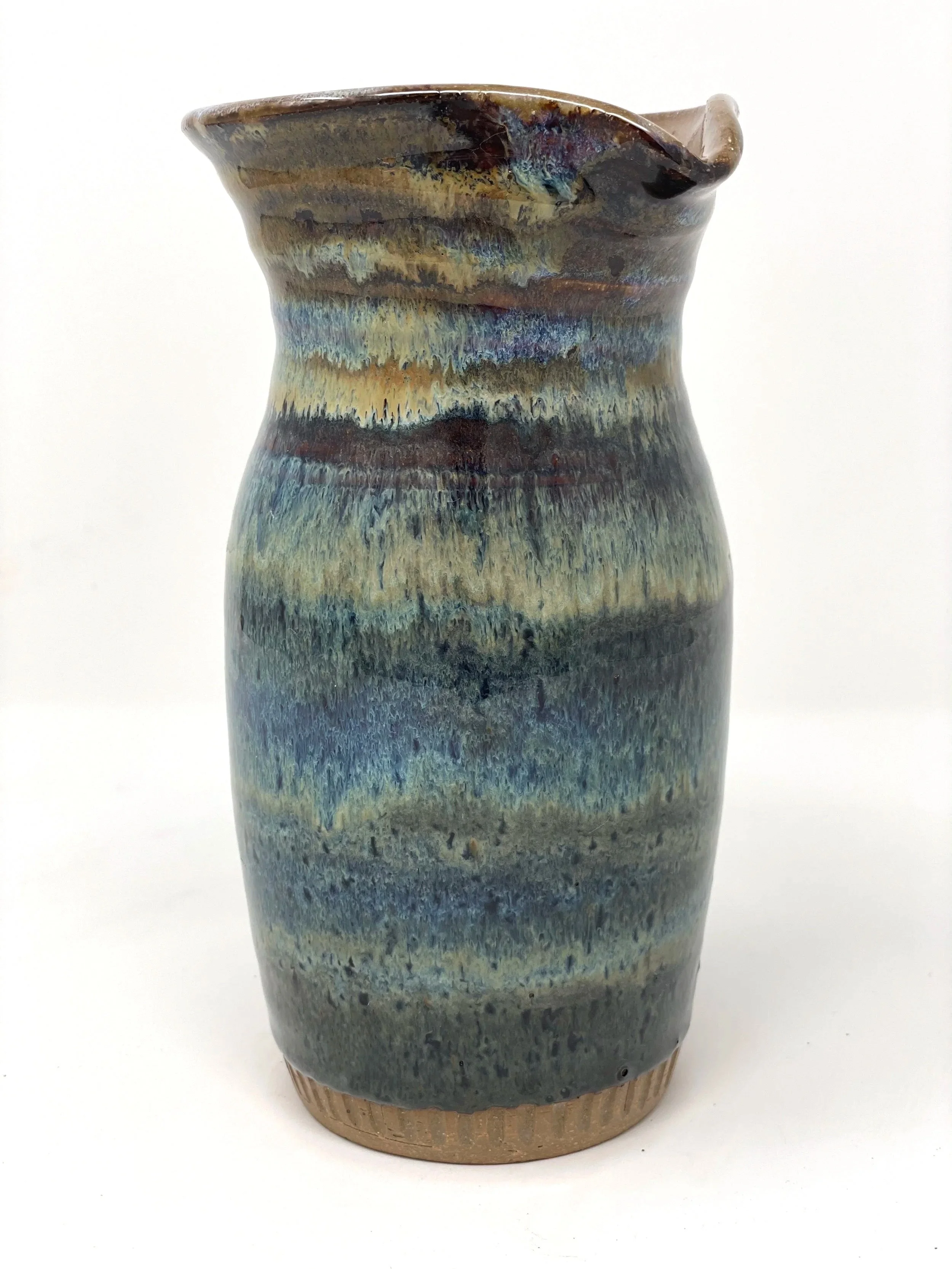 Ceramic vase with glaze in shades of blue, brown, and beige, with an uneven, textured surface and a small spout at the rim.