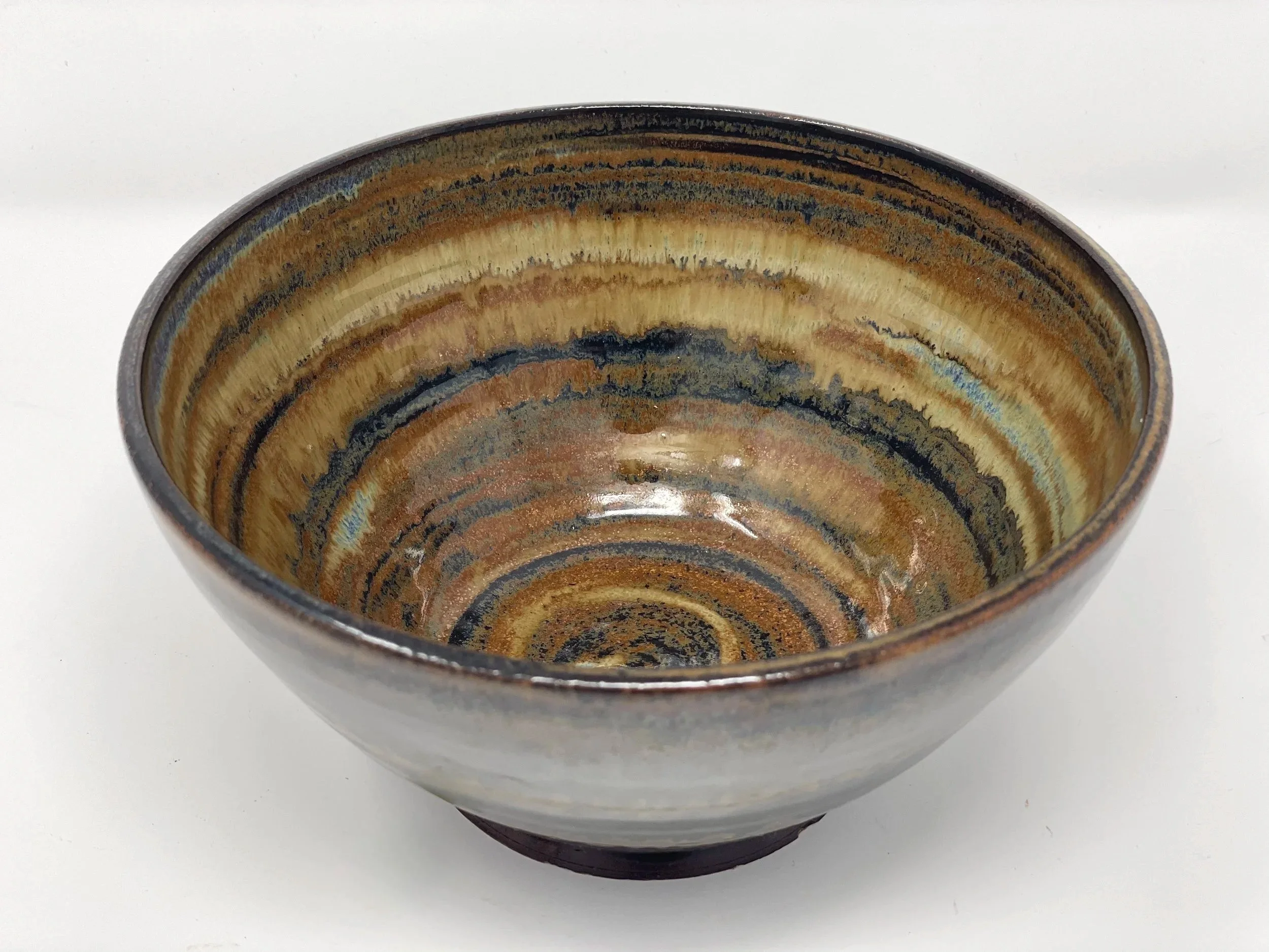 A ceramic bowl with a multicolored, swirled glaze pattern on a white surface.