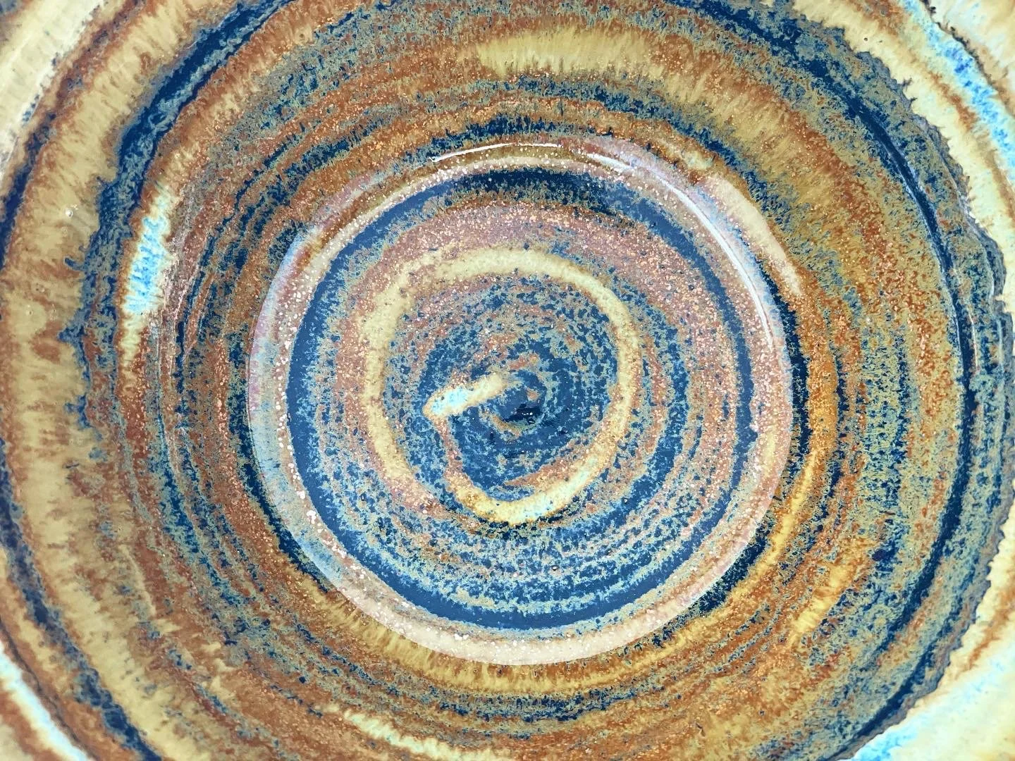 Close-up view of a ceramic piece with concentric circular patterns in shades of blue, brown, and beige.