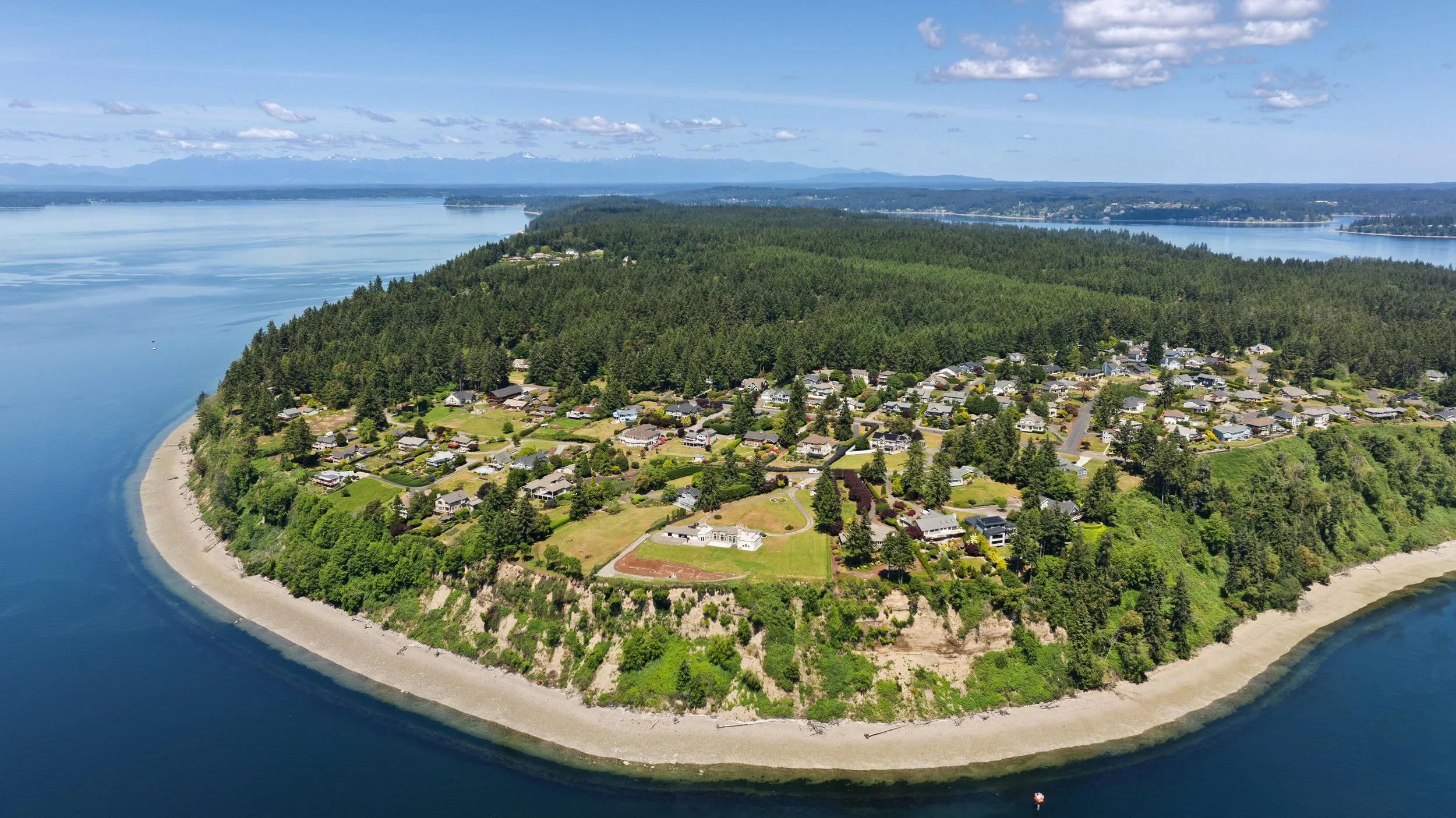 Aerial drone photograph of Fox Island, Washington showcasing the waterfront shoreline, residential neighborhood, and Puget Sound captured by Spenrol Media.