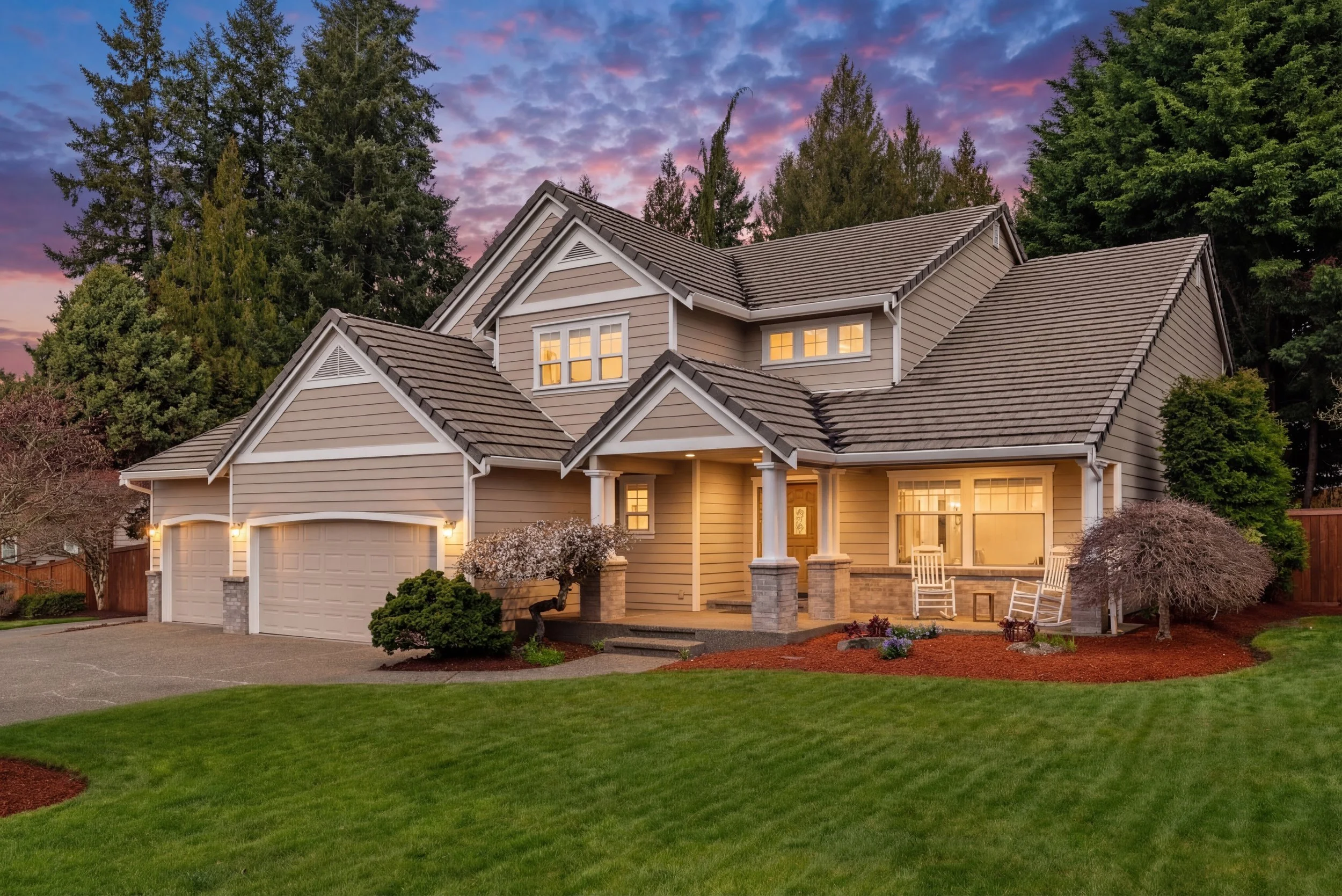 Daylight to twilight conversion of a luxury home exterior with warm interior lighting and colorful sunset sky by Spenrol Media.