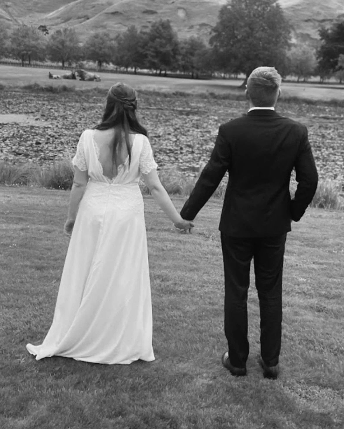 Back view of bride and groom.  She has an open back wedding dress with lace detailing