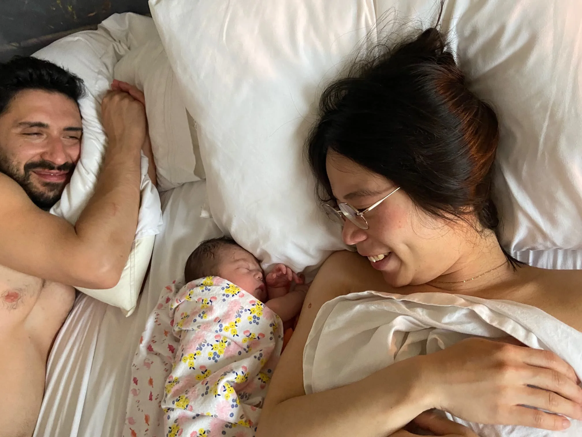 parents-smiling-at-newborn-baby-in-bed.jpg