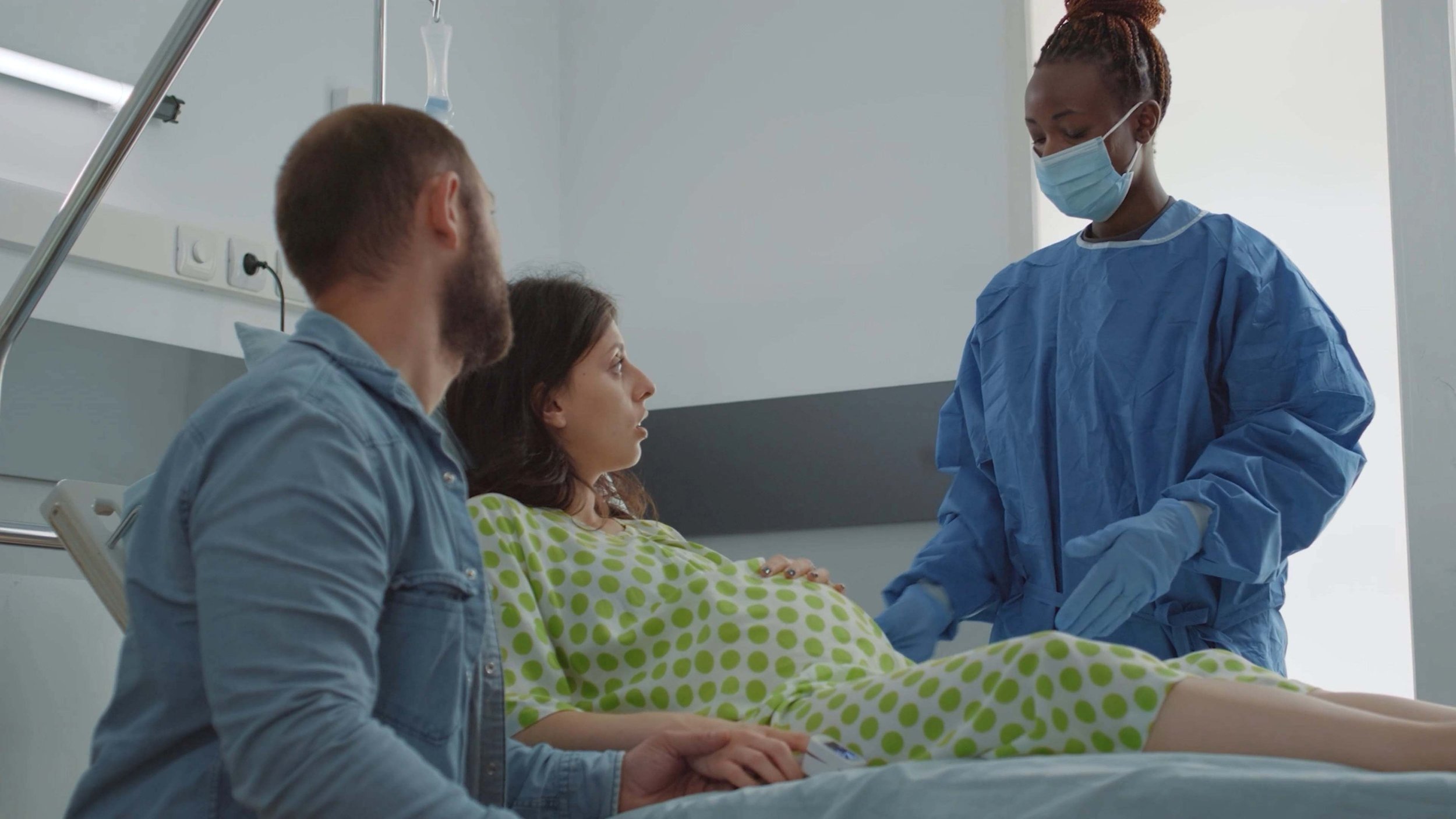 pregnant couple talking with gowned medical professional