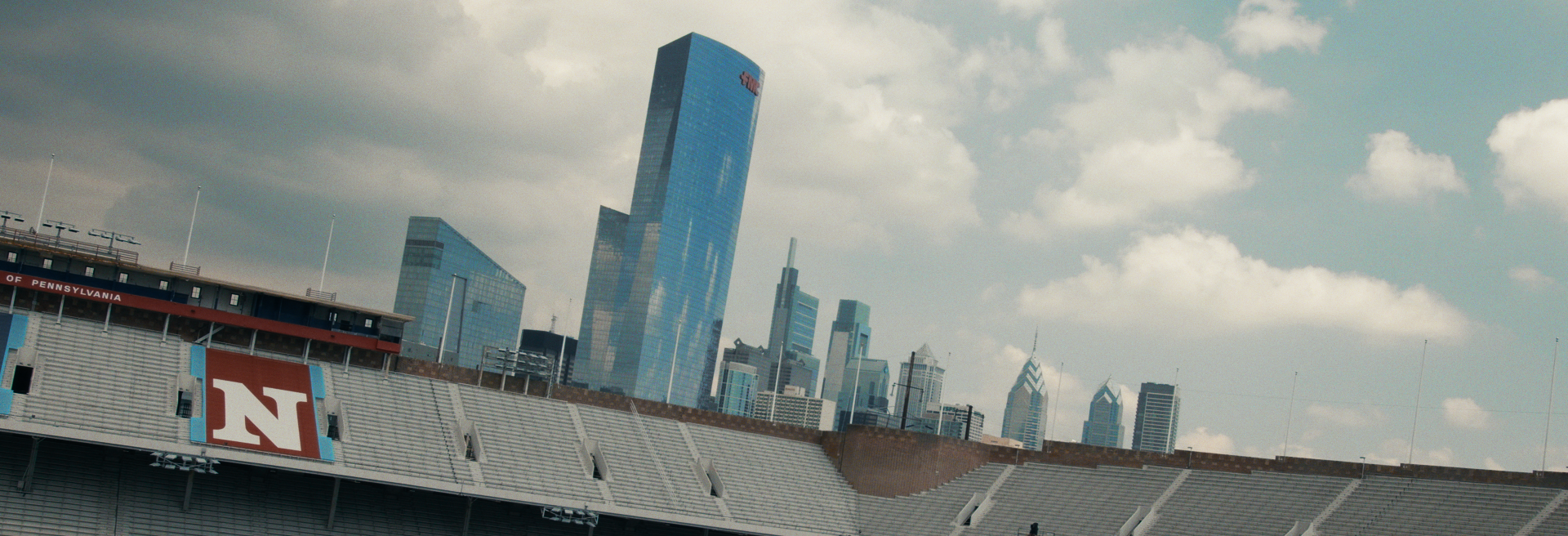 Wide view of Lincoln Financial Field in Philadelphia with the Philadelphia skyline in the background, including tall skyscrapers and partly cloudy sky.