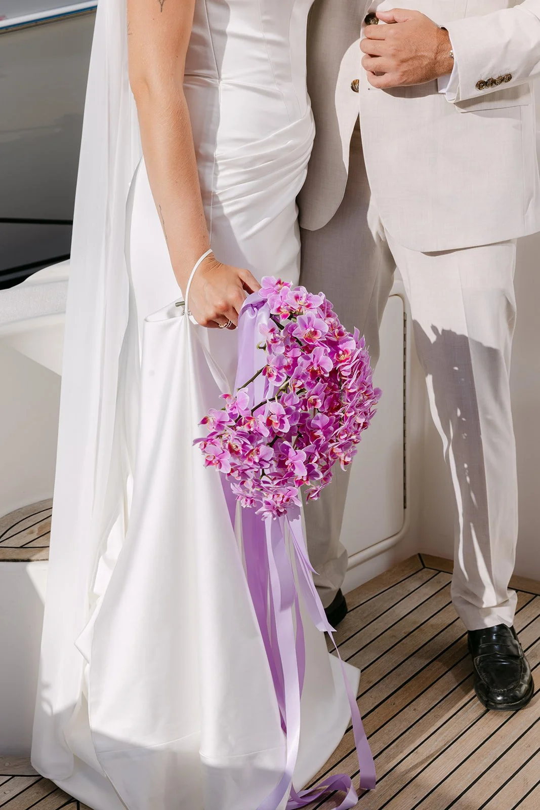 Jane Hill bridal gown with flowing chiffon neck scarf styled on yacht with pink and green flowers