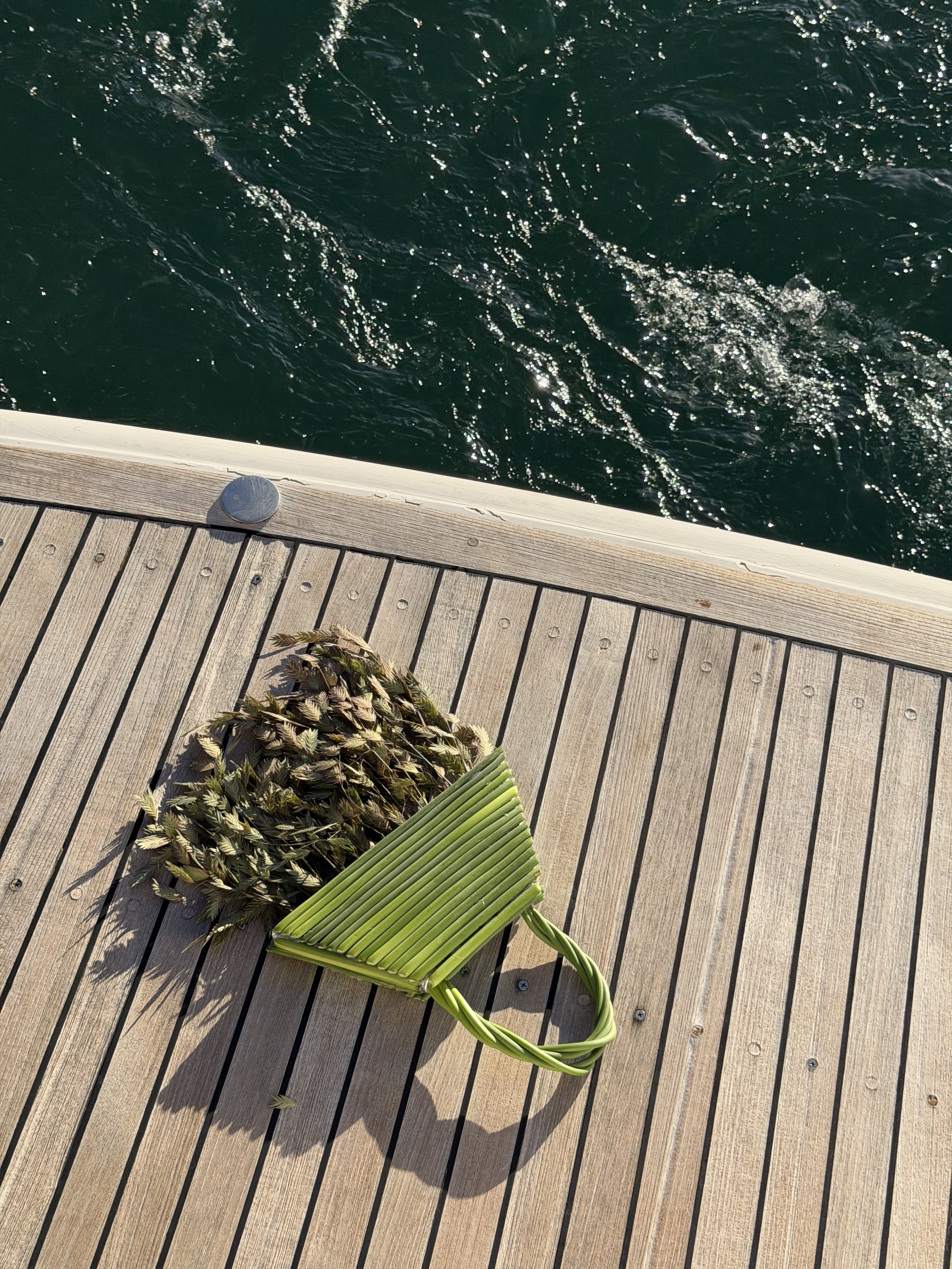 Green floral bridal handbag styled aboard yacht during contemporary wedding editorial