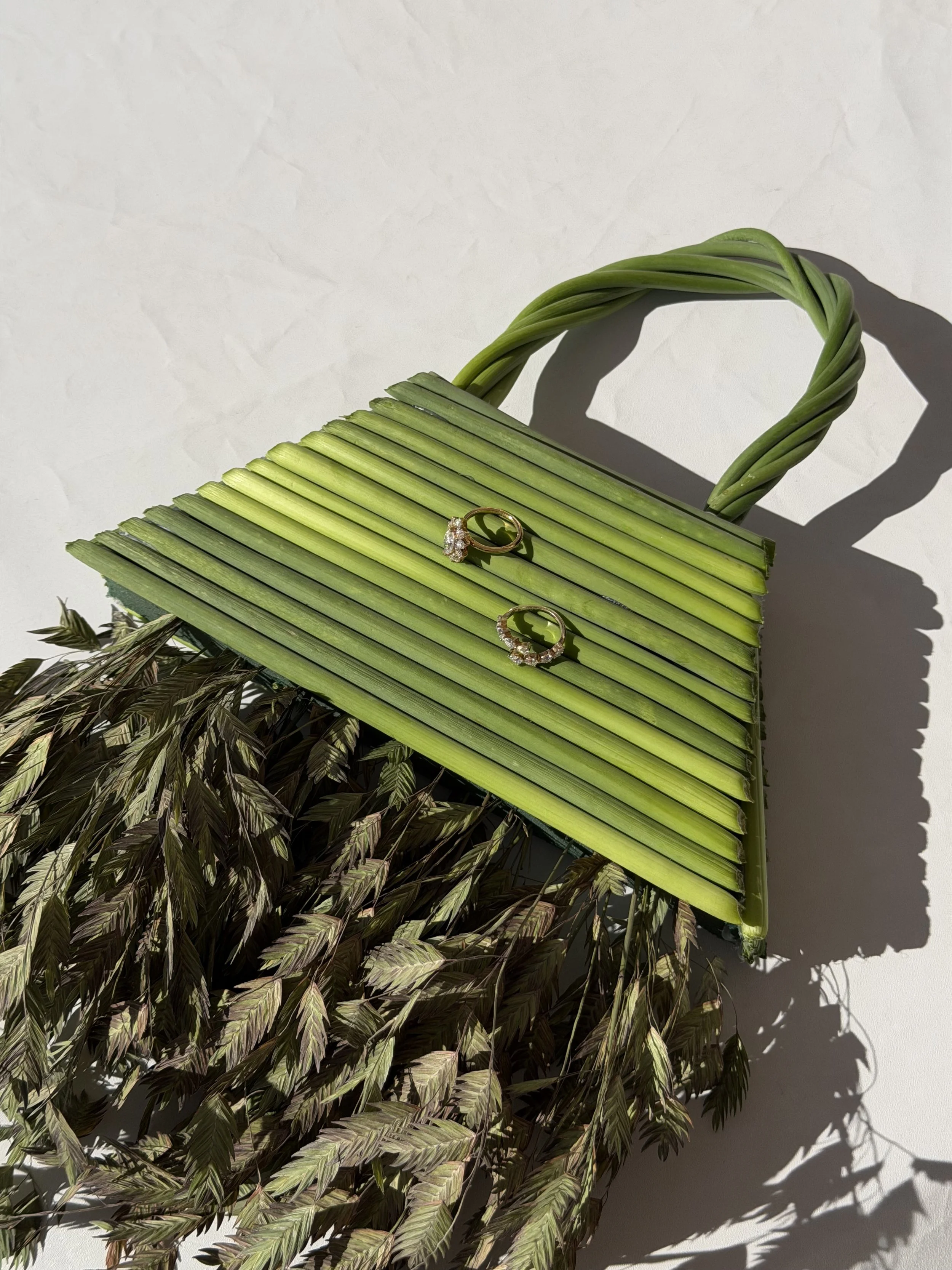 Close-up of green floral handbag with luxury bridal styling and soft pink flowers