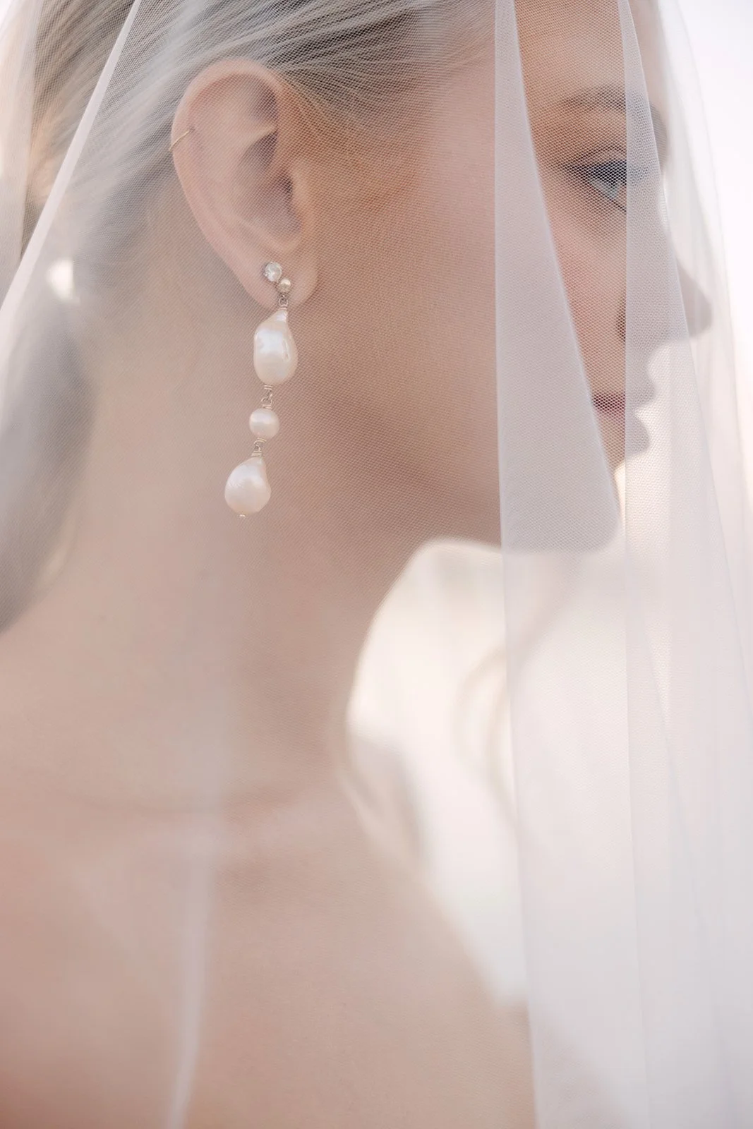 Close-up of bridal earring beneath soft veil during luxury wedding editorial