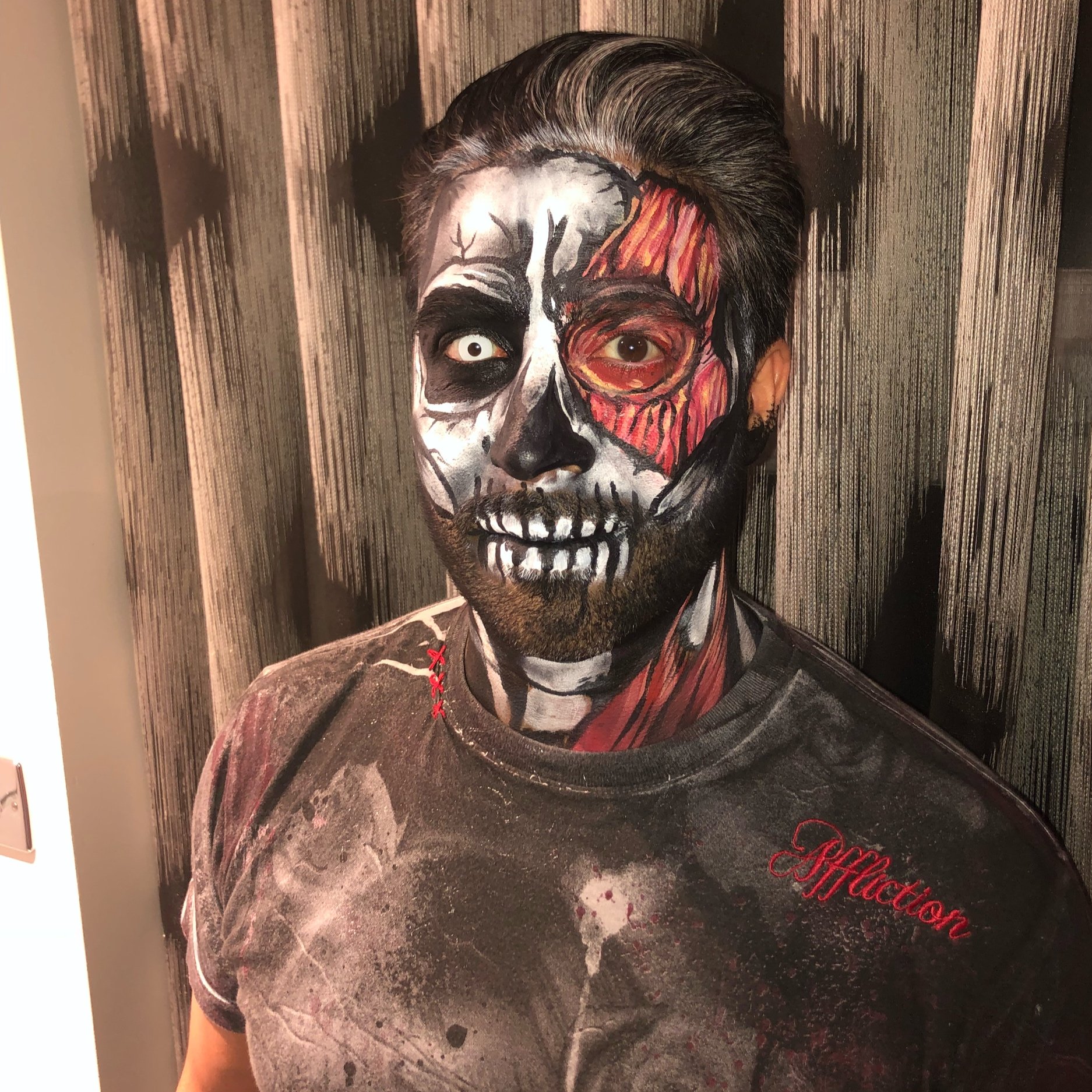 The photo features a dramatic Halloween look with a skull and flesh design, expertly crafted by Suhaila’s makeup artistry.
