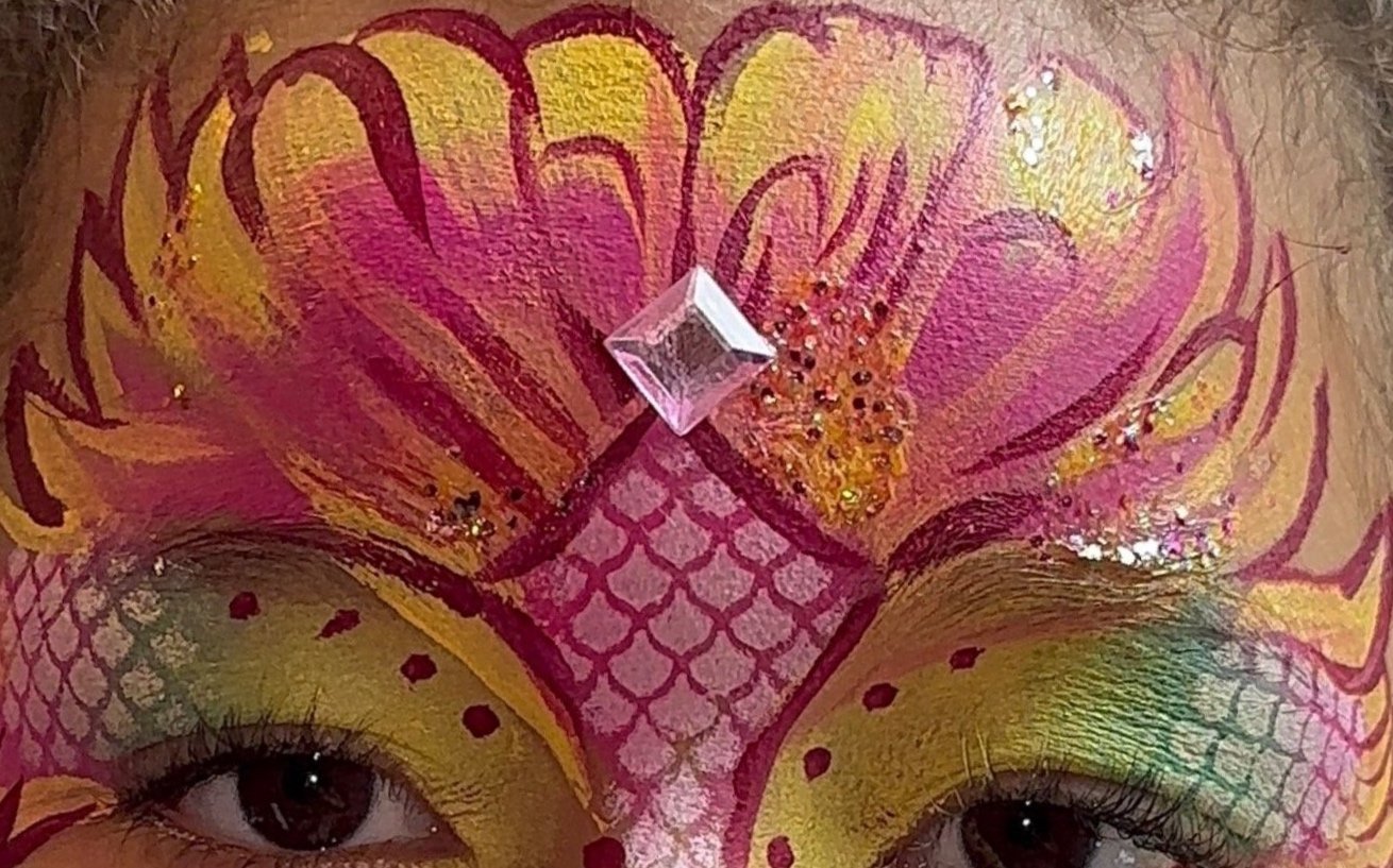The photo features enchanting mermaid face painting for children, beautifully designed by Suhaila to capture whimsical and vibrant underwater magic.