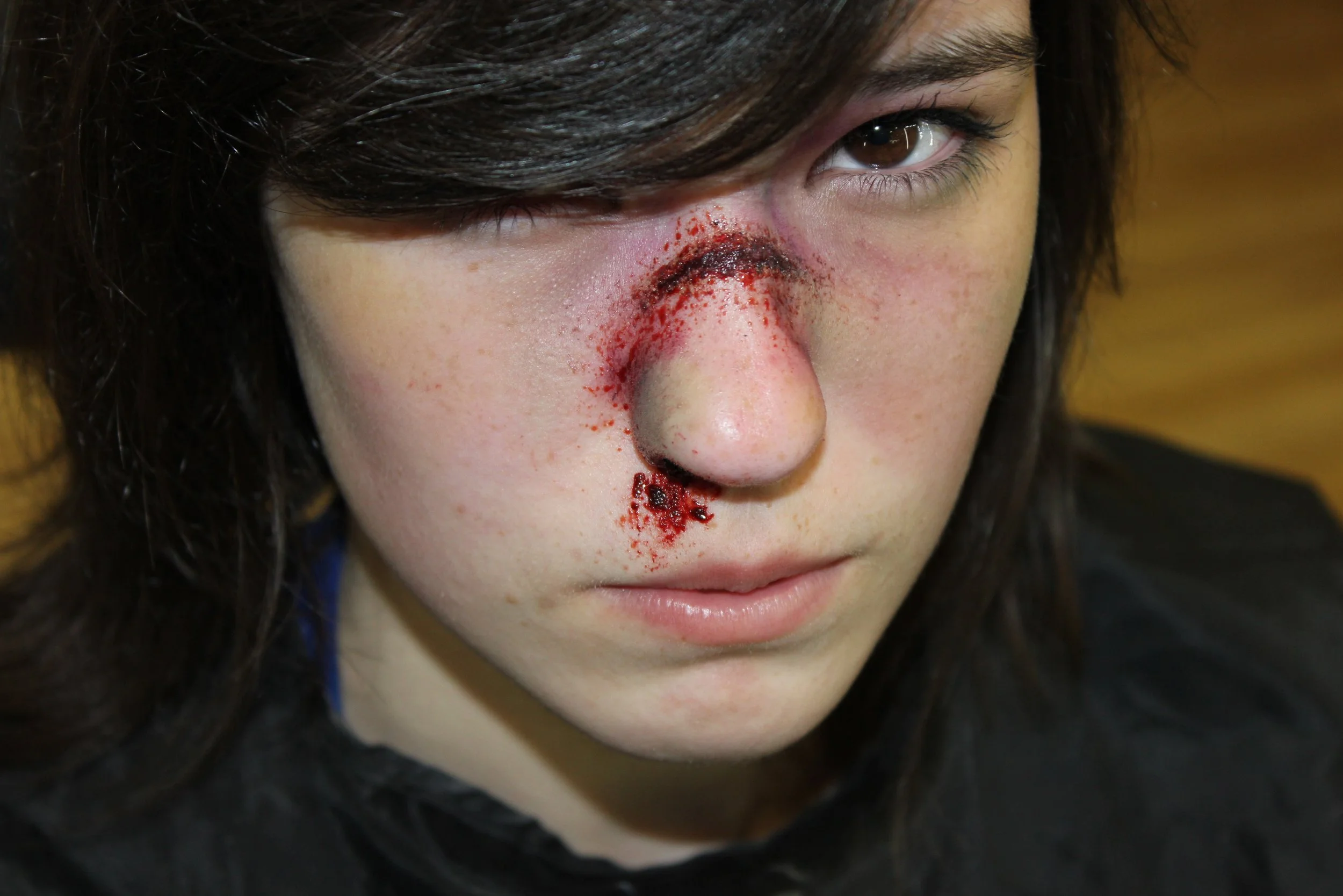 The photo showcases a dramatic broken nose effect, expertly crafted with special effects makeup by Suhaila. The realistic detailing enhances the striking and intense visual impact of the injury.