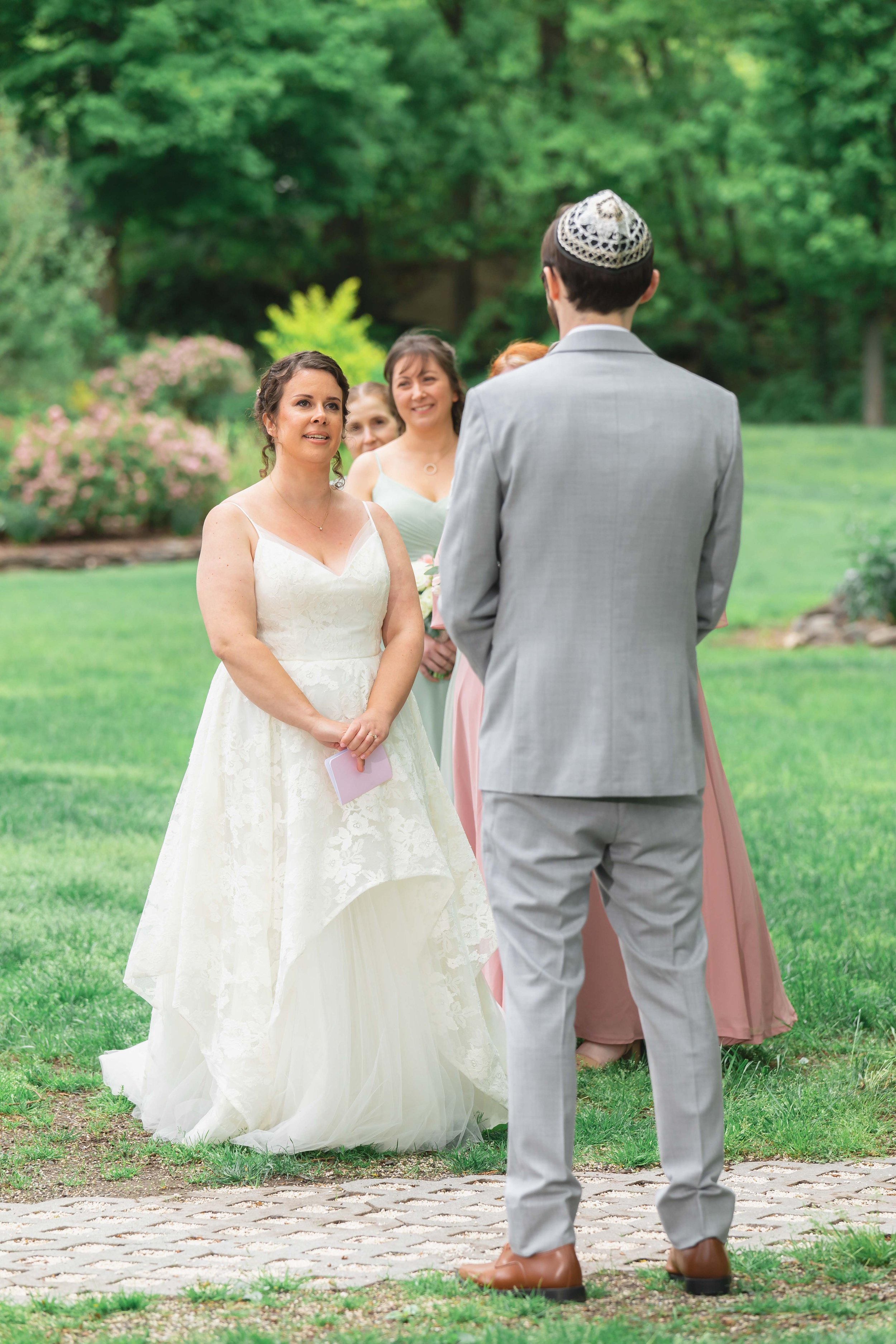bride reads vows in verdant summer garden at Saugerties Performing Arts Factory chic industrial wedding venue in upstate NY