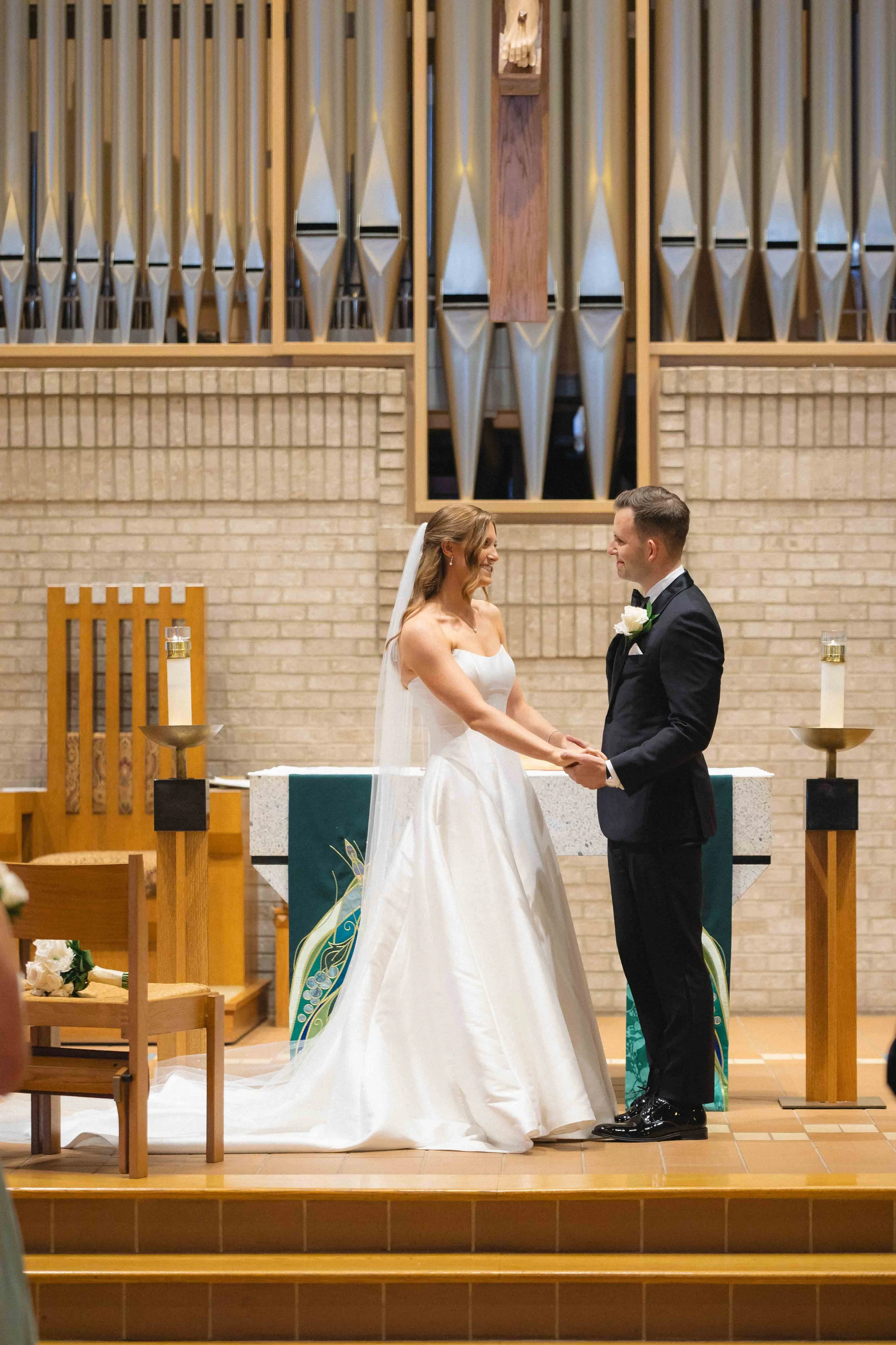 Bride and groom holding hands during their wedding ceremony inside a church.