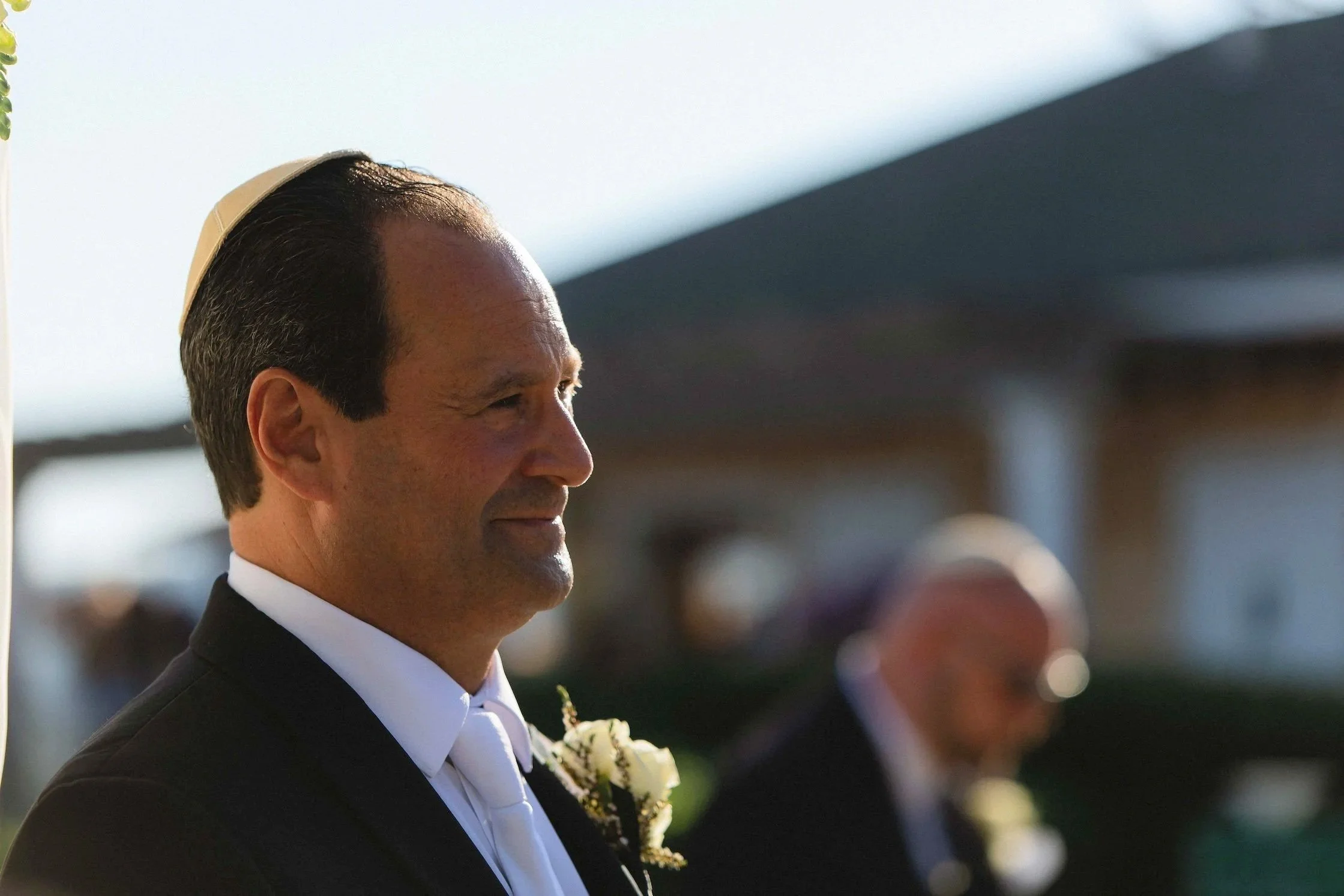 Groom waits under chuppah as bride walks towards wedding ceremony during processional on steps on back lawn of the sagamore resort in bolton landing on Lake George NY