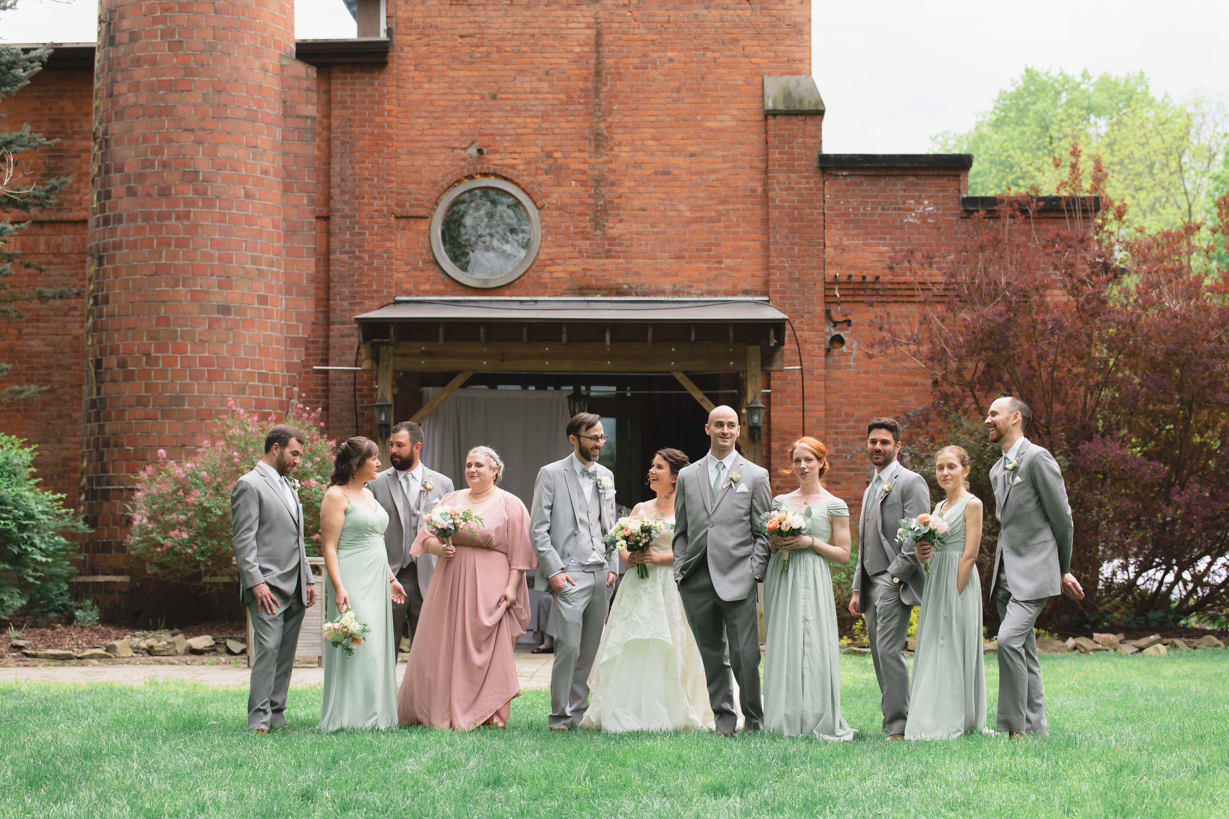 bride and groom with full wedding party in garden outside industrial bridal suite in summer at Saugerties Performing Arts Factory wedding venue in upstate NY