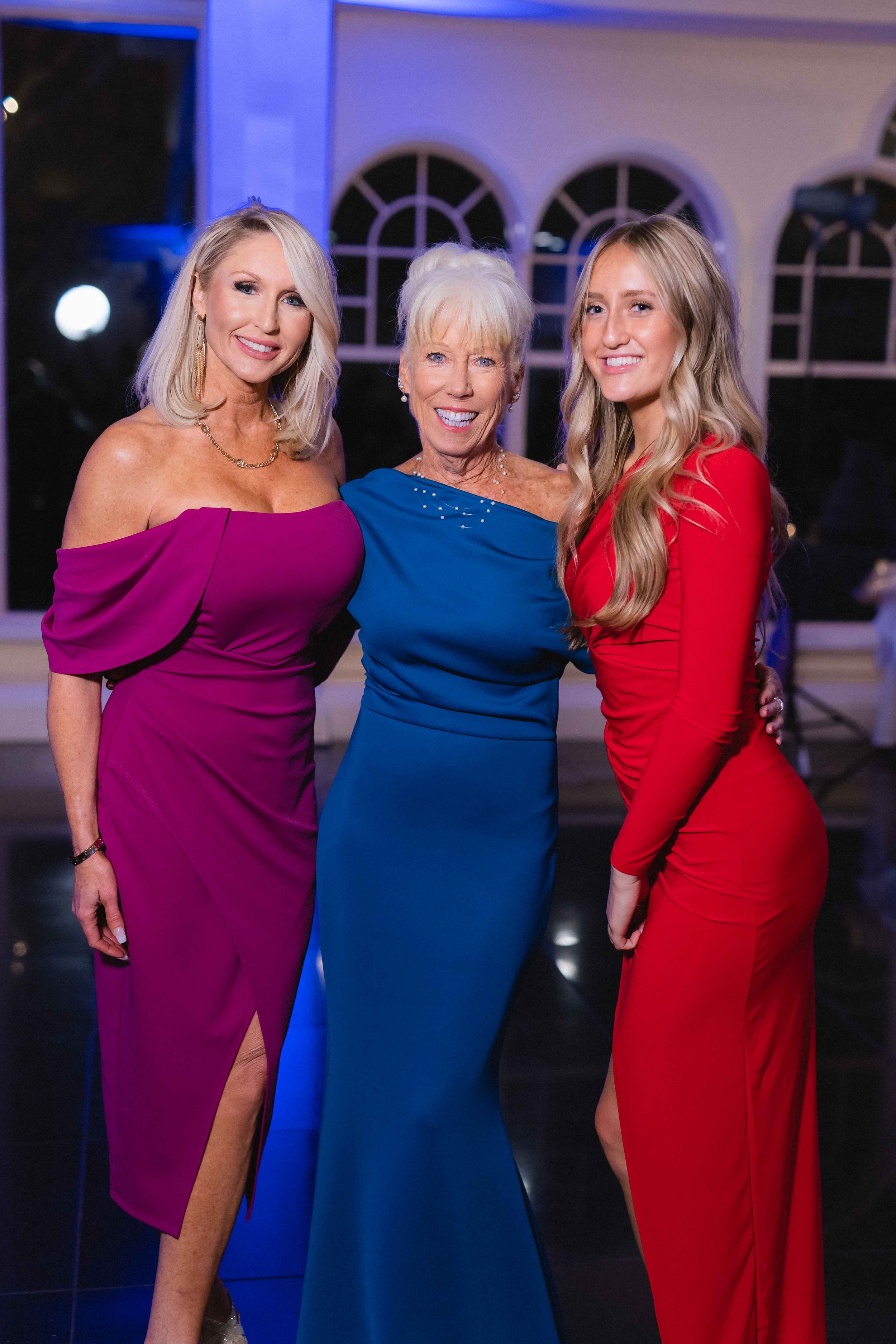 Friends and relatives of the bride pose in red blue and magenta saturated primary color dresses during reception at the waterview wedding venue in monroe ct