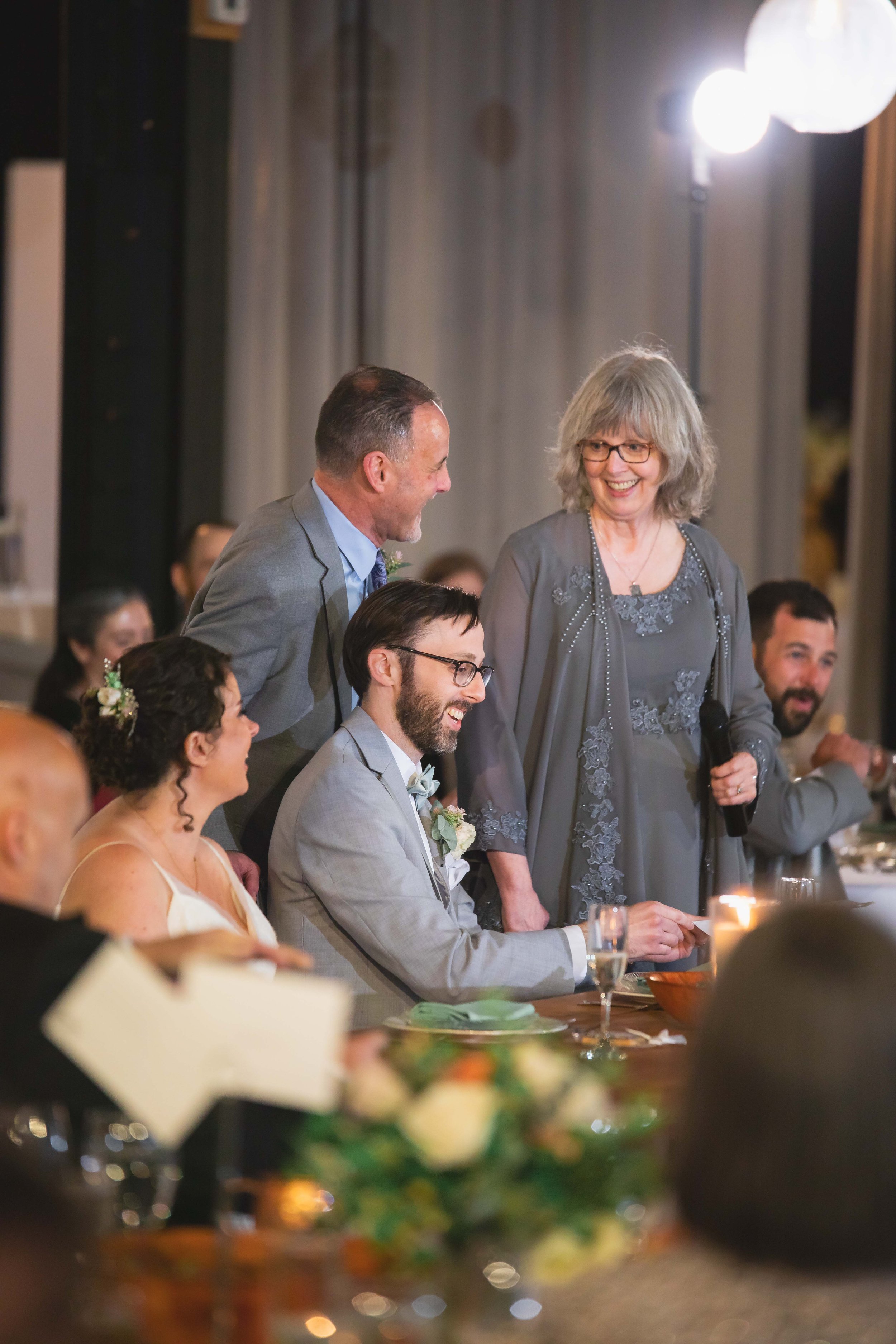 groom's parents give toast during dinner at reception at Saugerties Performing Arts Factory chic industrial wedding venue in upstate NY