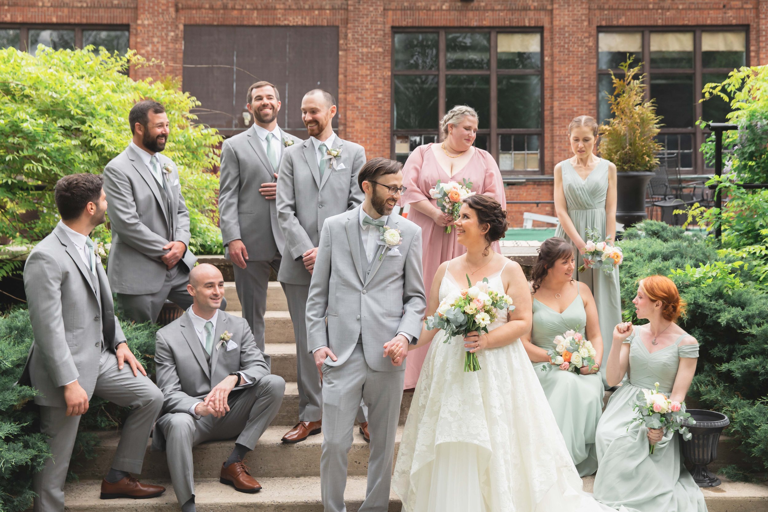Bride and groom with full wedding party in natural casual poses in verdant summer garden and at Saugerties Performing Arts Factory industrial wedding venue in upstate NY