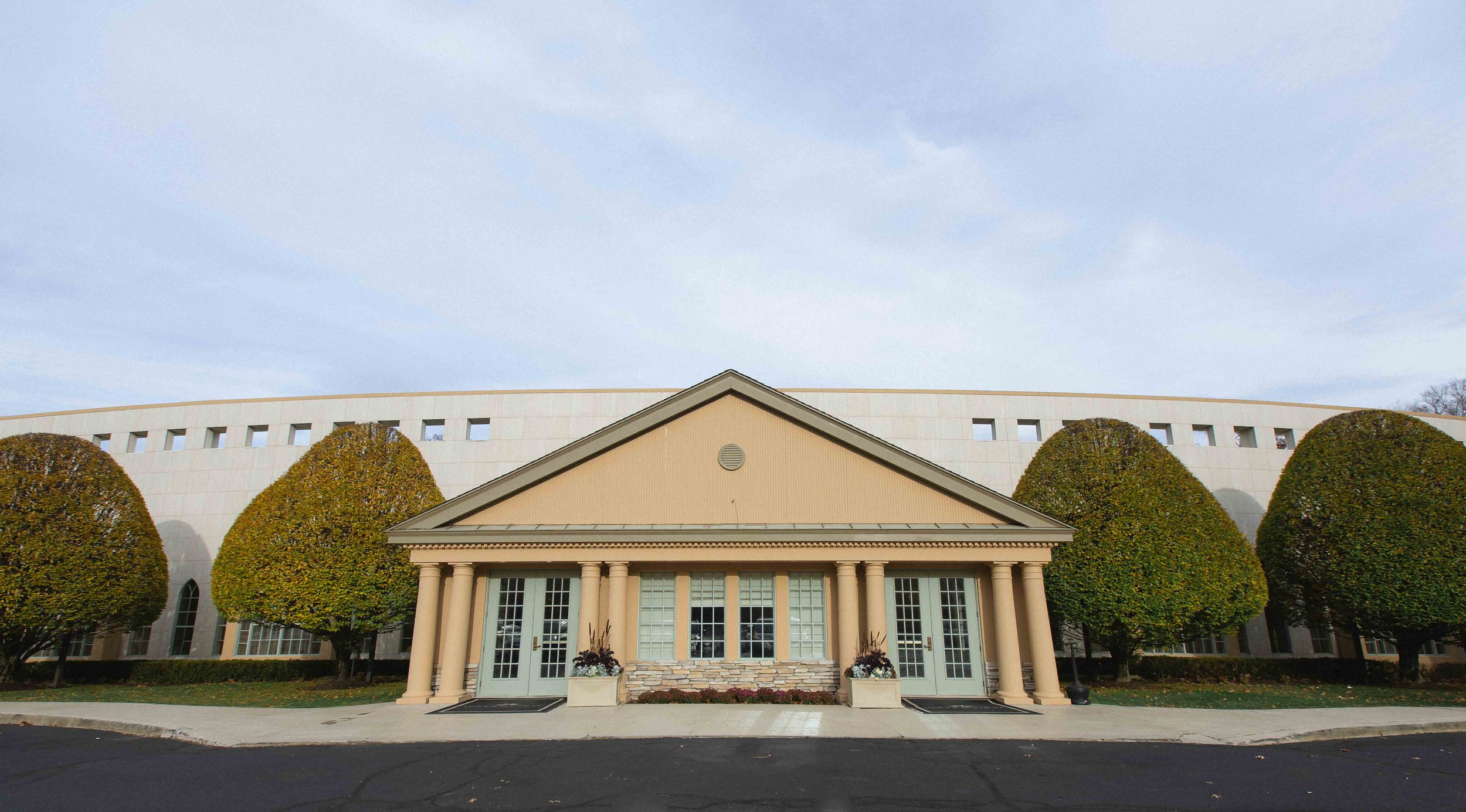The classical architecture of the main entrance doors of the waterview wedding venue in monroe ct flanked by large round well-manicured trees