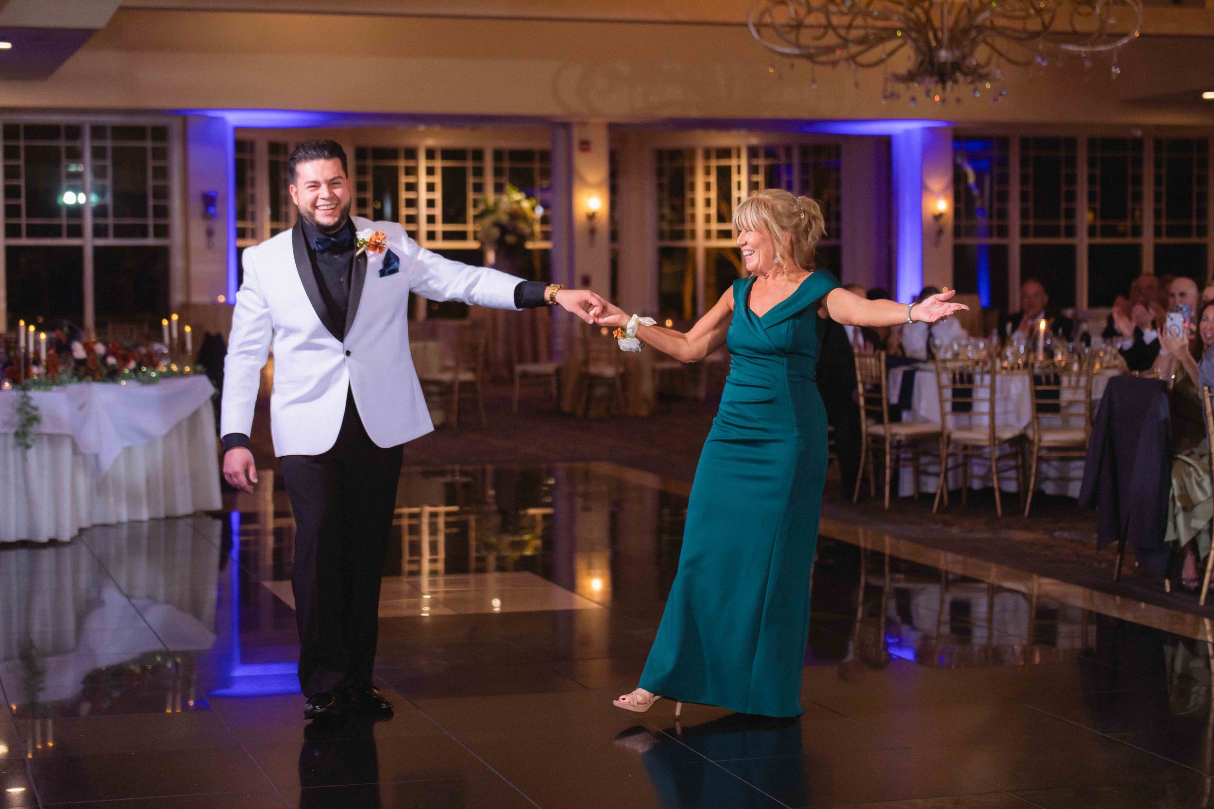 groom celebrates and bows after dancing with bride's mother in ballroom during reception at the waterview wedding venue in monroe ct