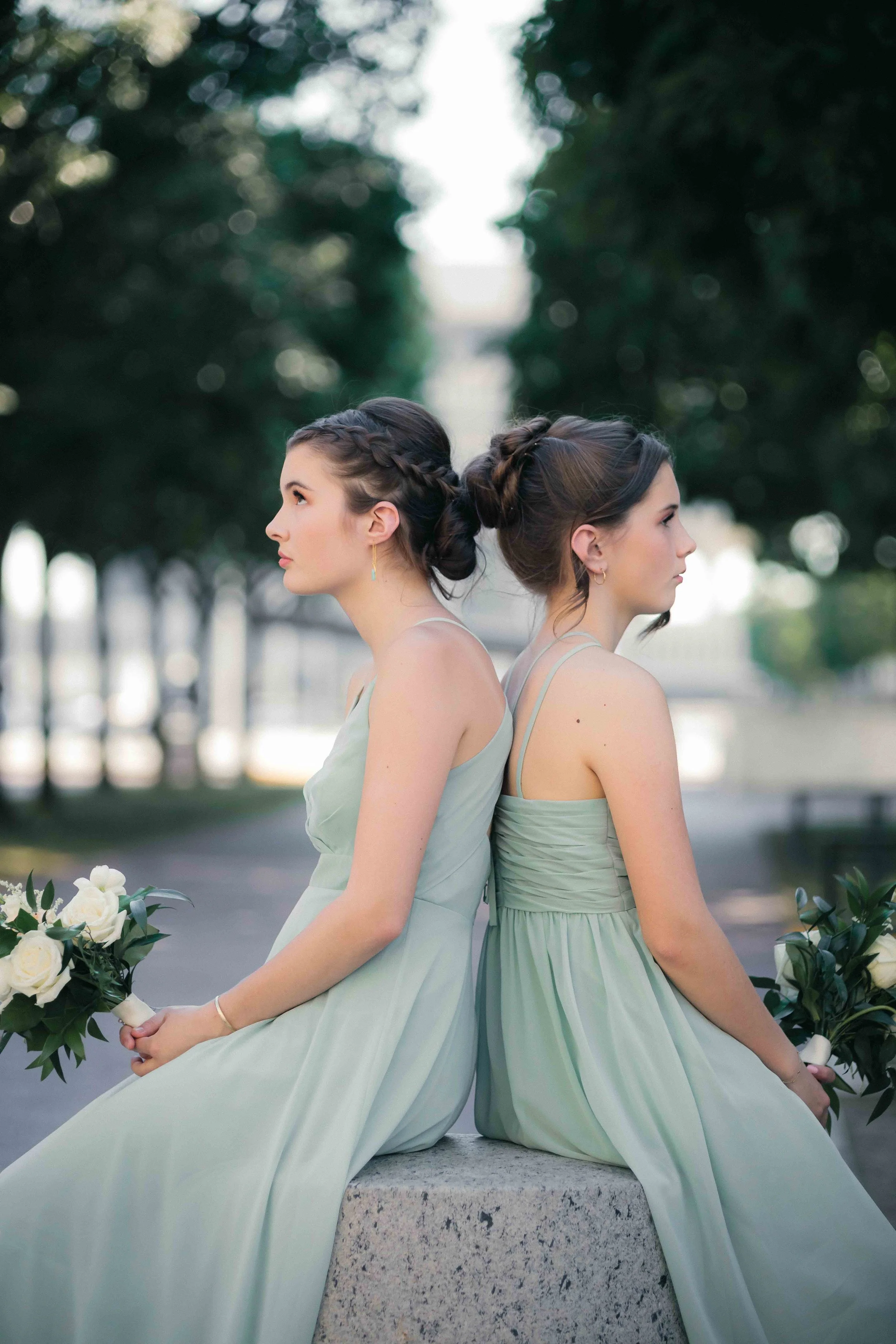 bridesmaids sitting with bouquets in Empire State Plaza during formal portraiture wedding party photography before wedding at the Renaissance Hotel in Albany NY