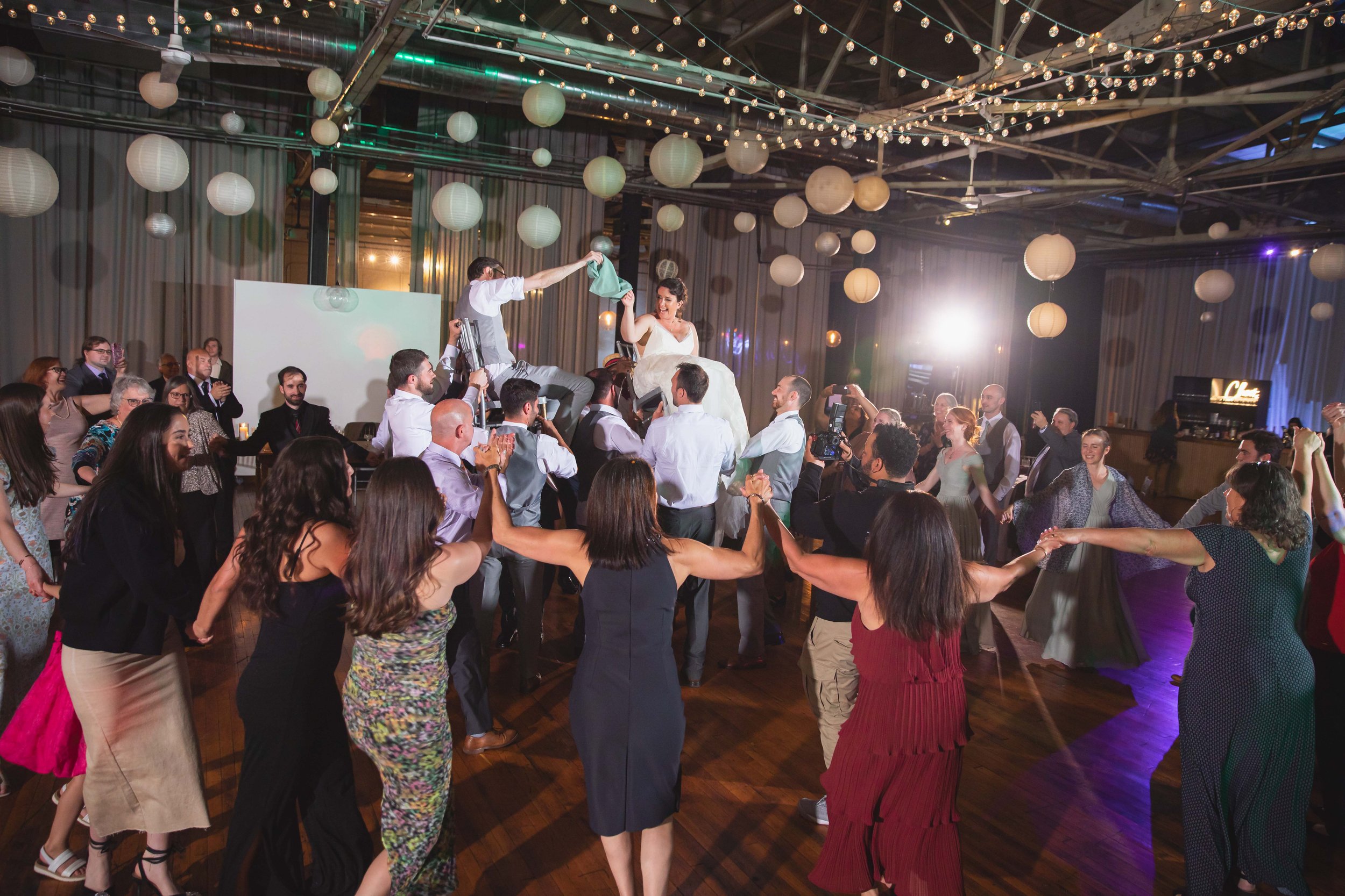 bride and groom smiling and laughing holding napkin during hora dance chair lift after reception dinner at Saugerties Performing Arts Factory chic industrial wedding venue in upstate NY
