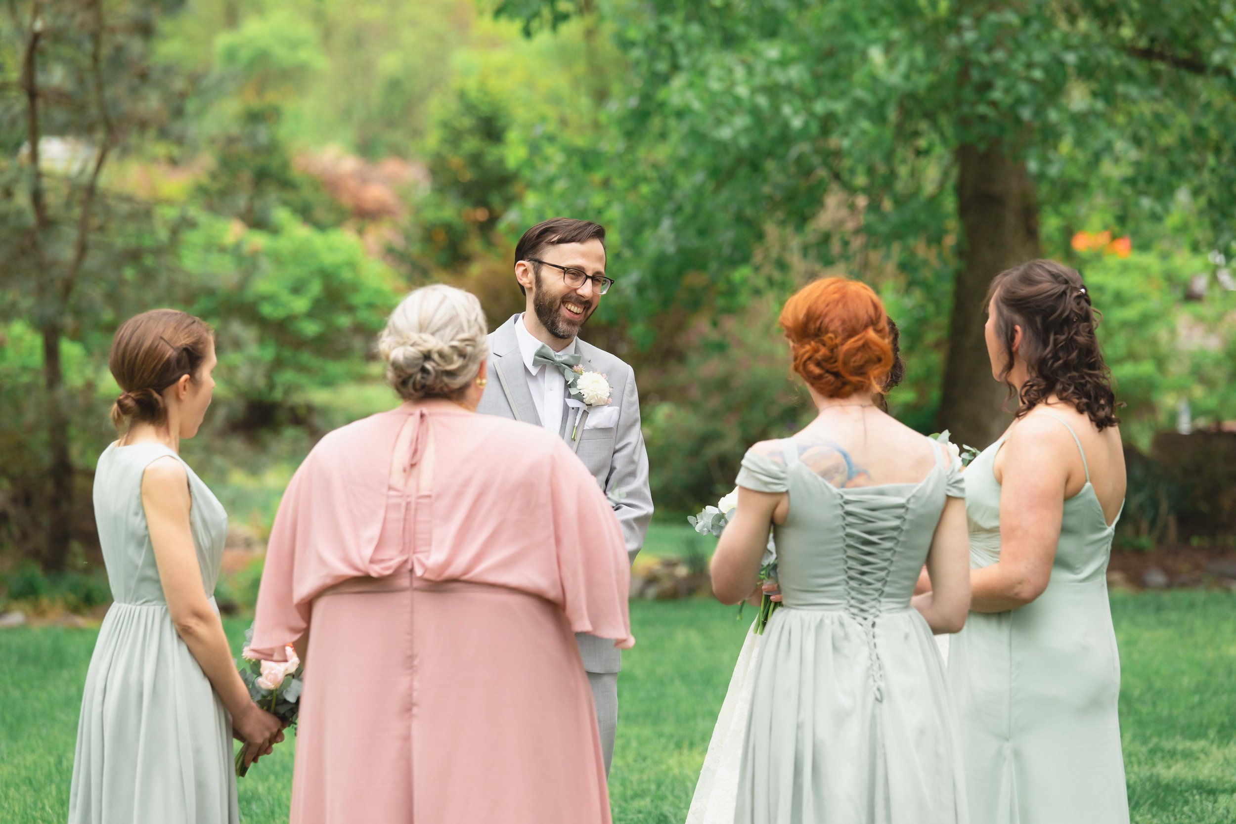 Groom smiles at bridal party after first look in garden in summer at Saugerties Performing Arts Factory wedding venue in upstate NY