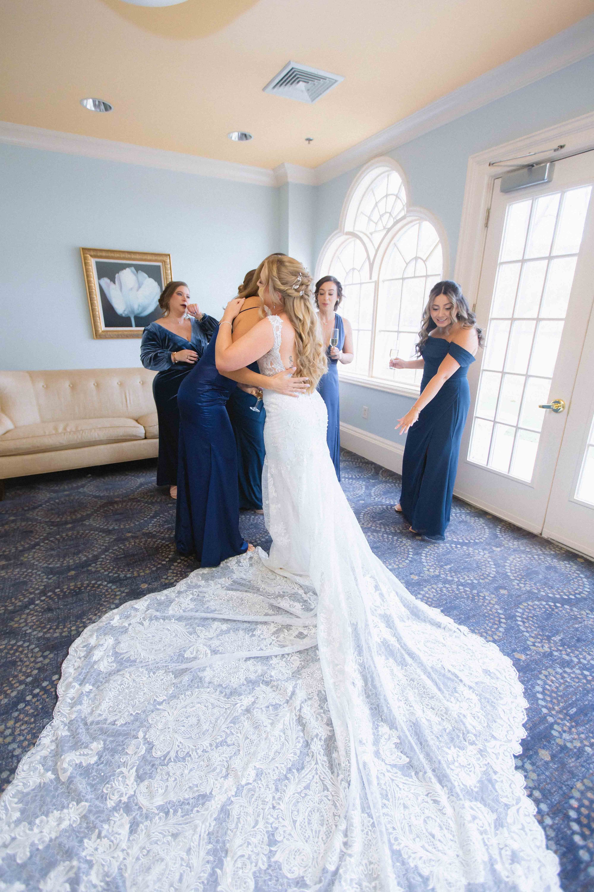 bride in wedding dress hugging bridesmaid after first look inside the bridal suite at the waterview wedding venue in monroe ct