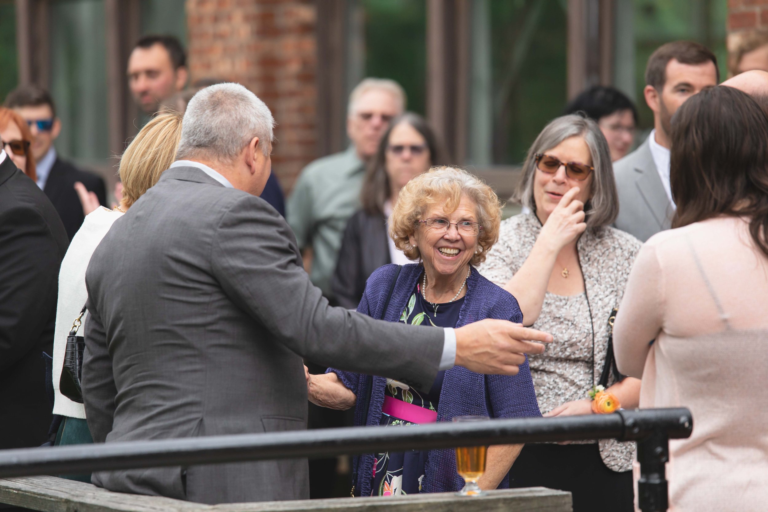 wedding guests smile talk and greet each other on patio after ceremony at Saugerties Performing Arts Factory chic industrial wedding venue in upstate NY