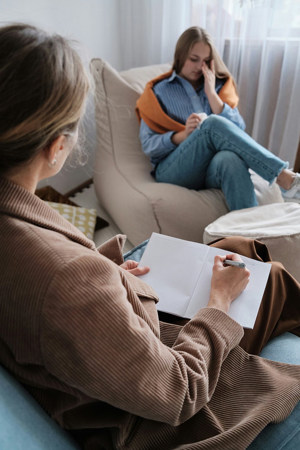 In-Home Counseling Services in Denver, CO, image of a therapist taking notes while a person shares their feelings.