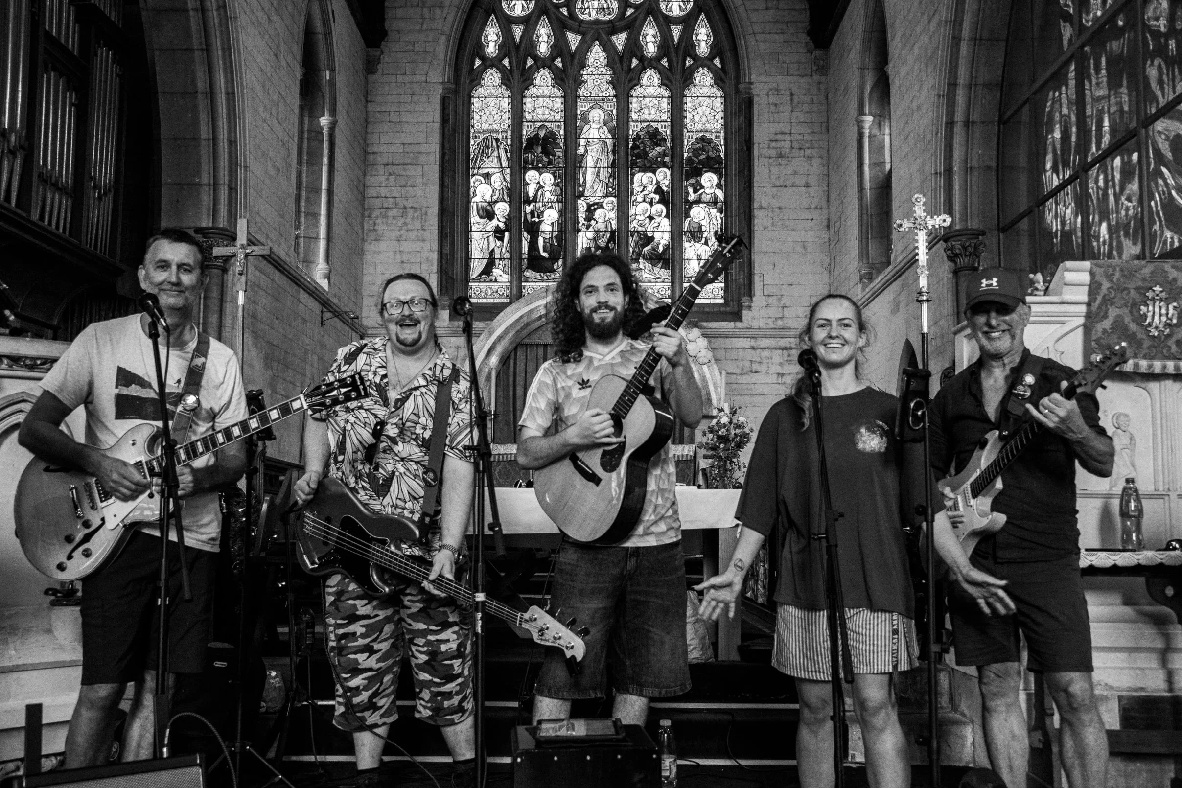 A digital group photograph of "The Hubcaps", a local band based in Axminster Devon. The setting is St. Michael's Church in Beer and the photo is in B&W.