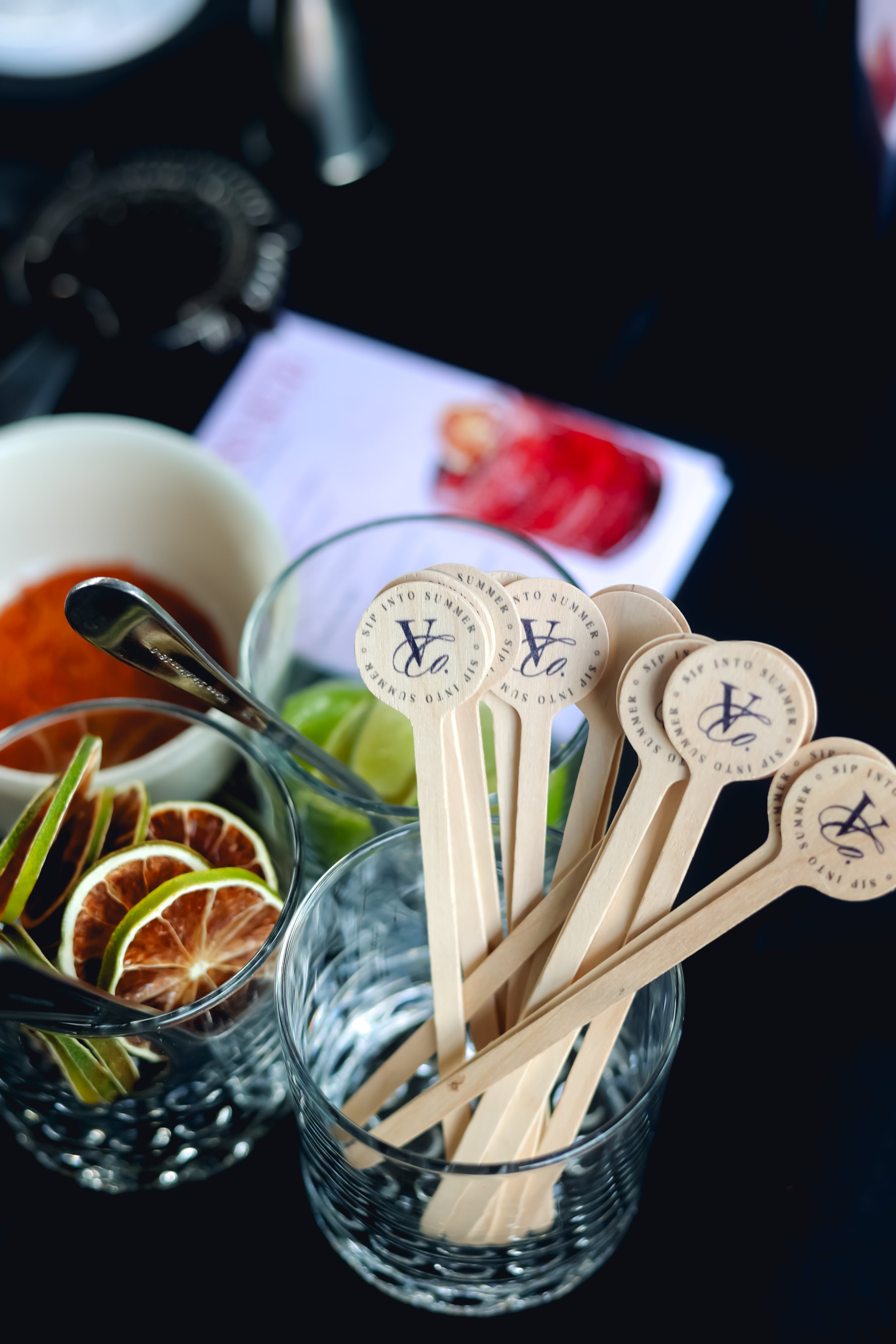Glass of wooden stir sticks labeled 'Sip into summer. '