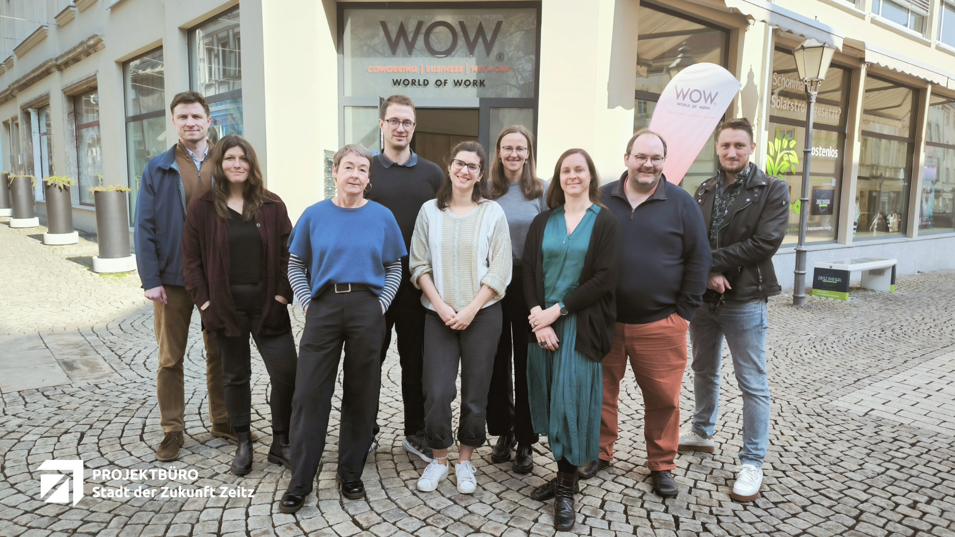 Gruppenfoto des Teams des Projektbüros Stadt der Zukunft Zeitz mit Vertretern der Stadtverwaltung vor dem Gebäude WOW am Roßmarkt in Zeitz, Sachsen-Anhalt.