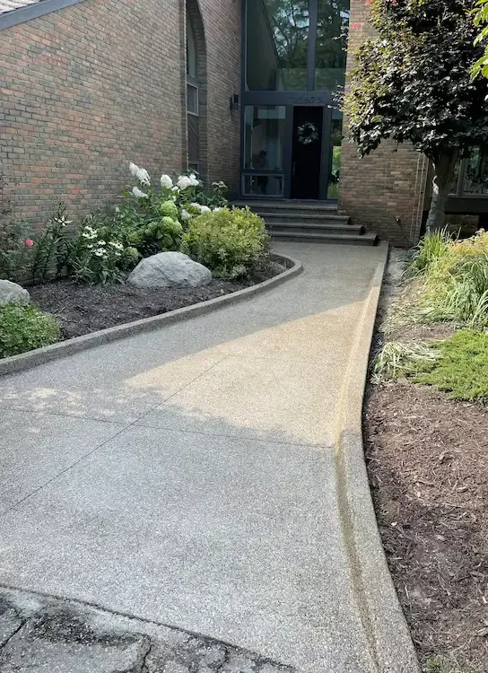 Custom curved exposed aggregate concrete walkway for a residential entrance in Michigan.