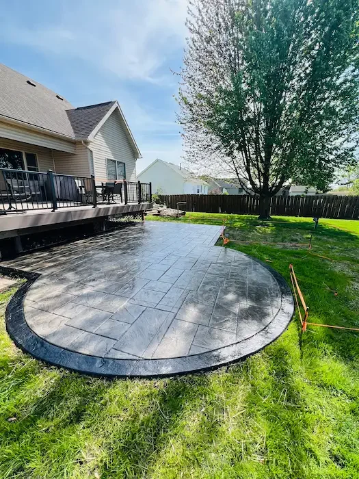 Backyard patio featuring a custom stamped concrete design and dark border finish.
