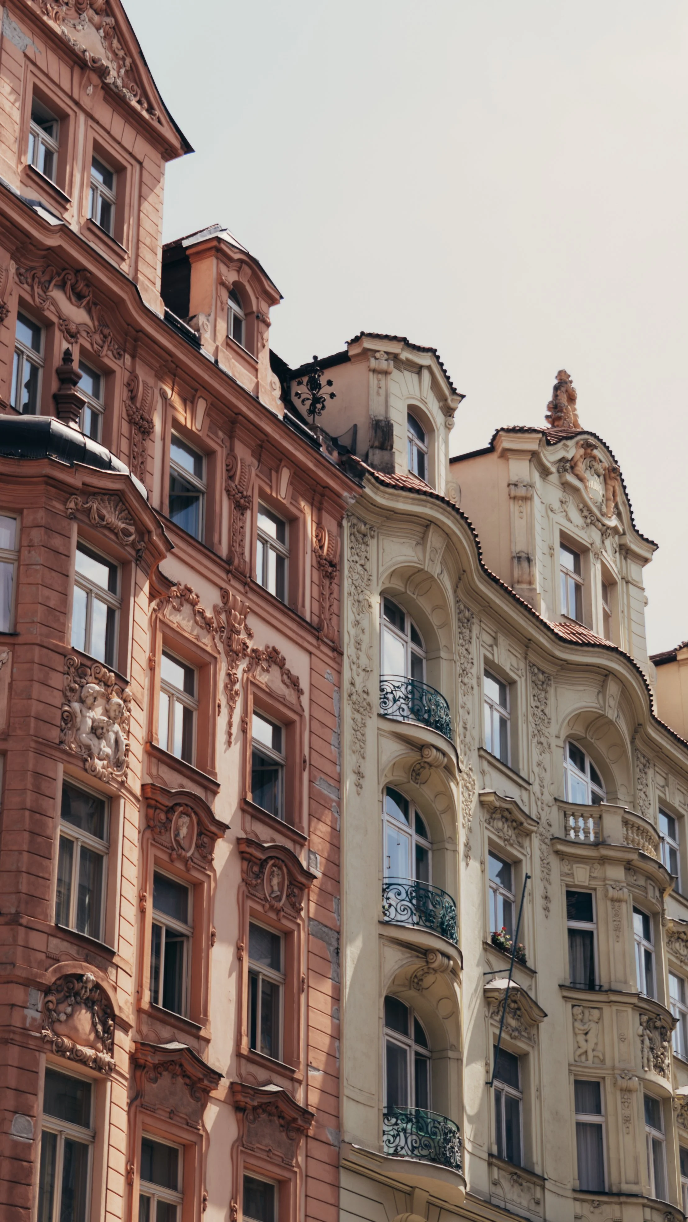 Facade of ornate European-style buildings with decorative architectural details, window balconies, and pastel-colored facades.