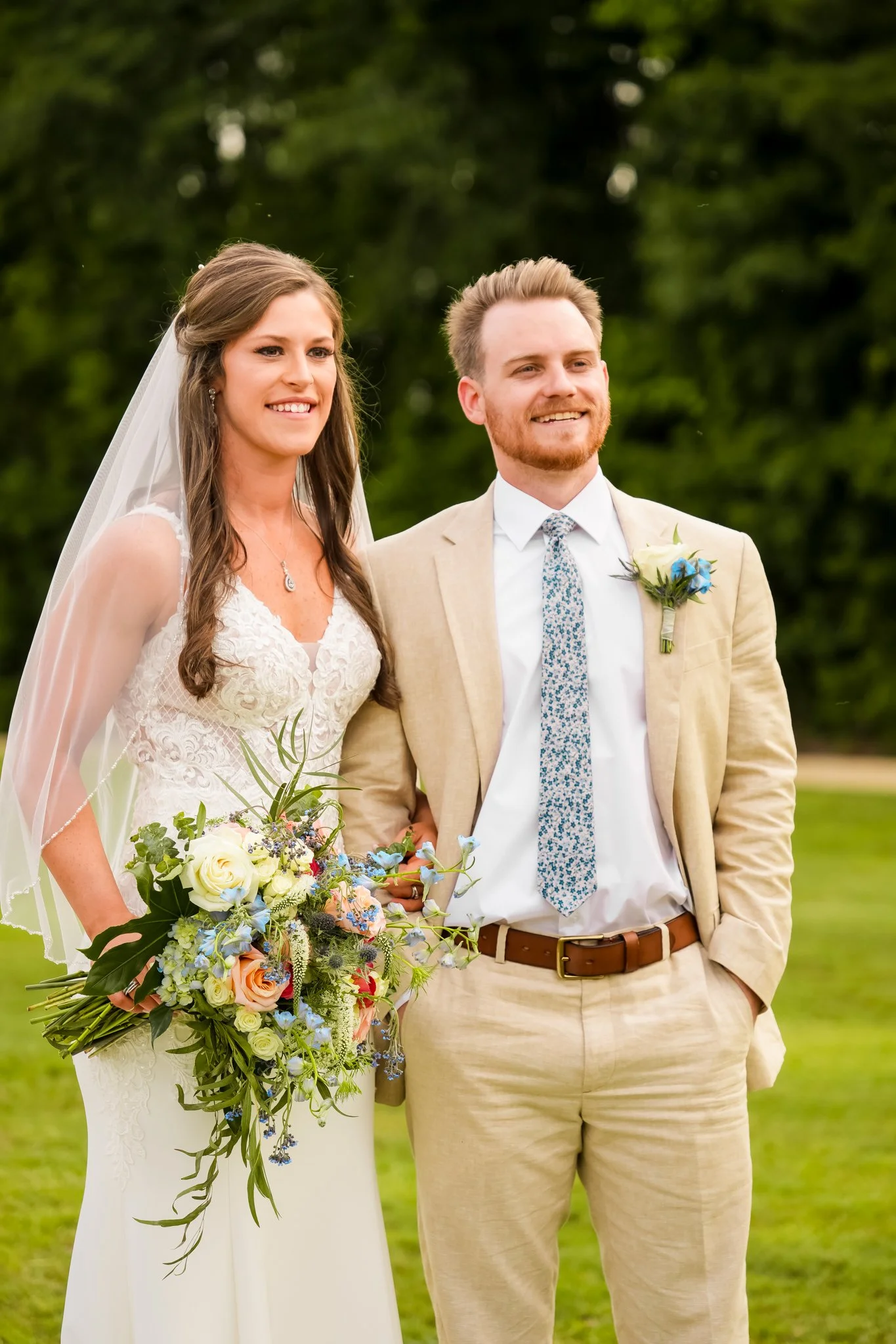 Bride and groom standing together with bouquet at their rustic summer wedding at The Barn at Broadslab in Benson, NC.