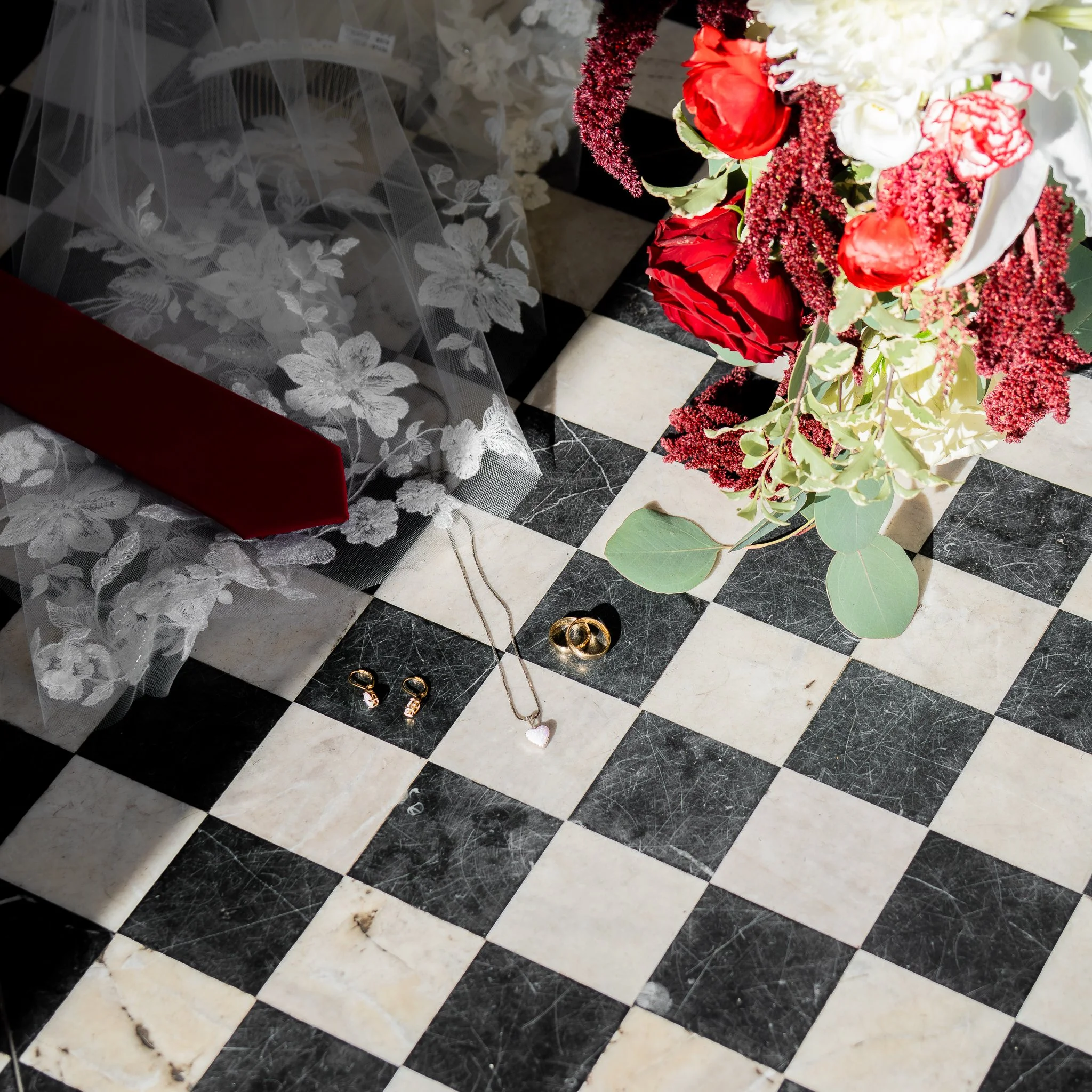 Jewelry and flower bouquet on black and white checkered floor.